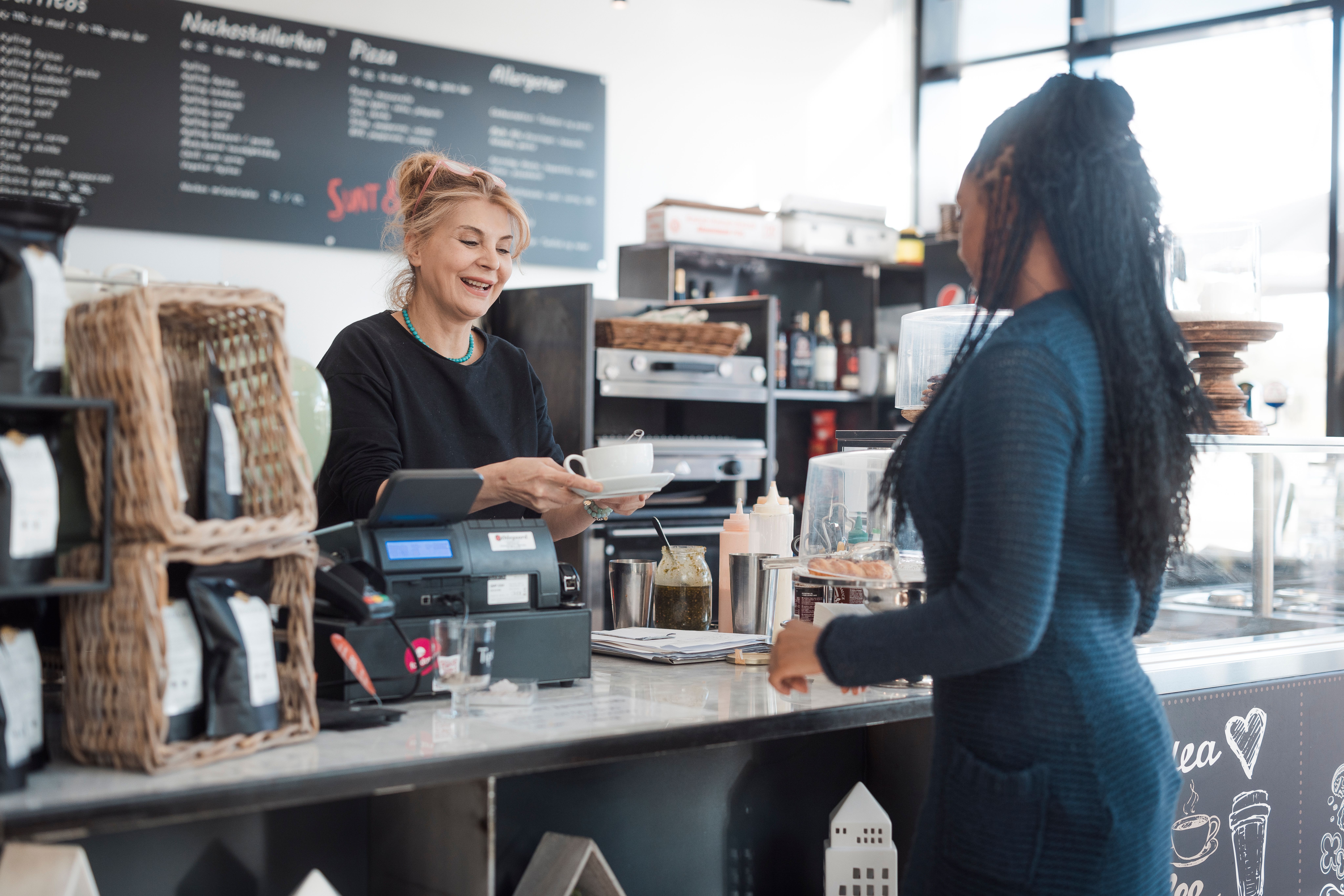 Dame på kafe serverer kaffe til en kunde