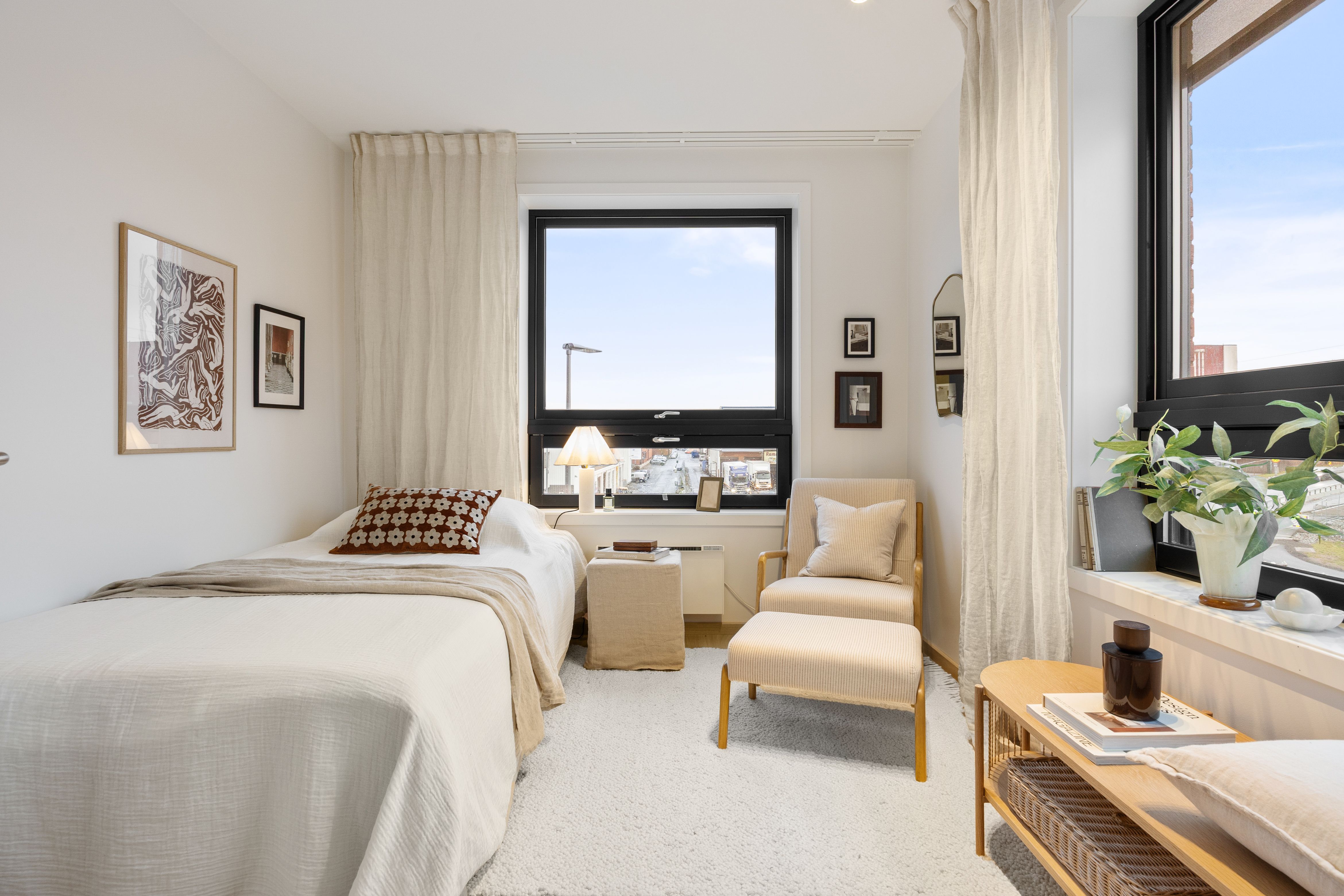 Soverom med seng og stol og oppbevaringsbenk.