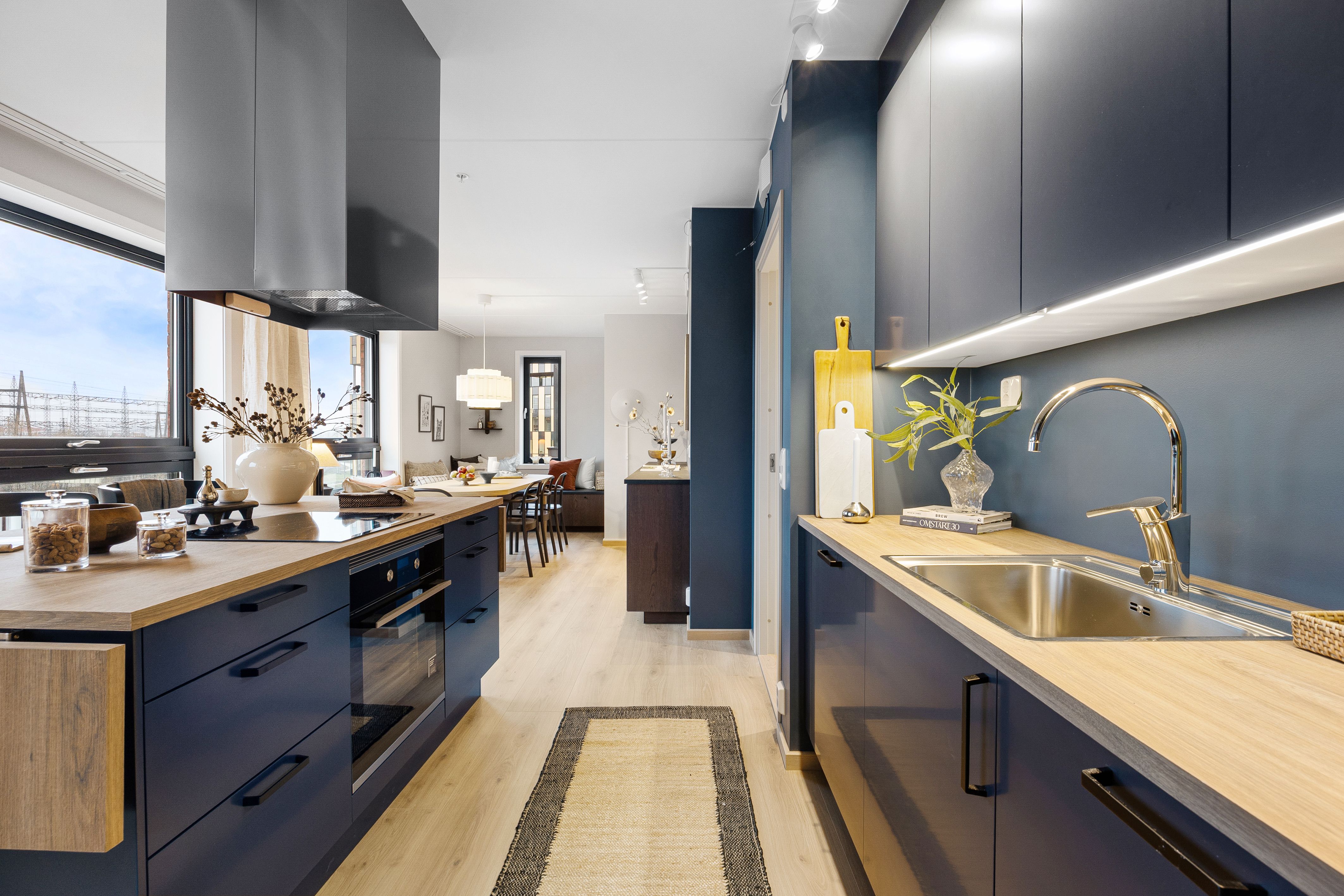 Kjøkken med kjøkkenbenk og kjøkkenøy. Spisebord i bakgrunnen