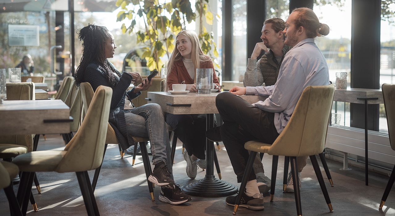 Fire unge voksne sitter rundt et bord