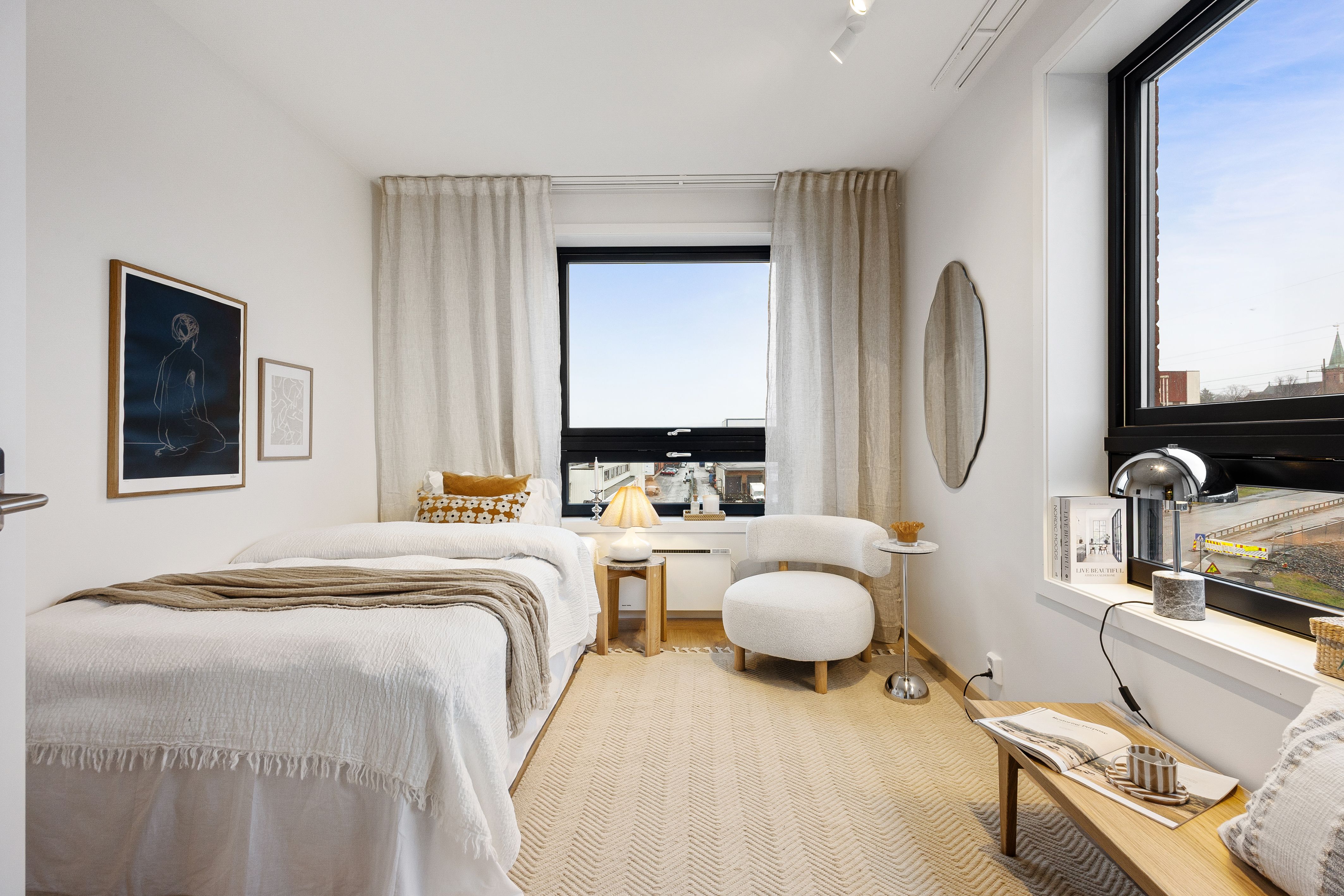 Soverom med seng og stol. To vinduer