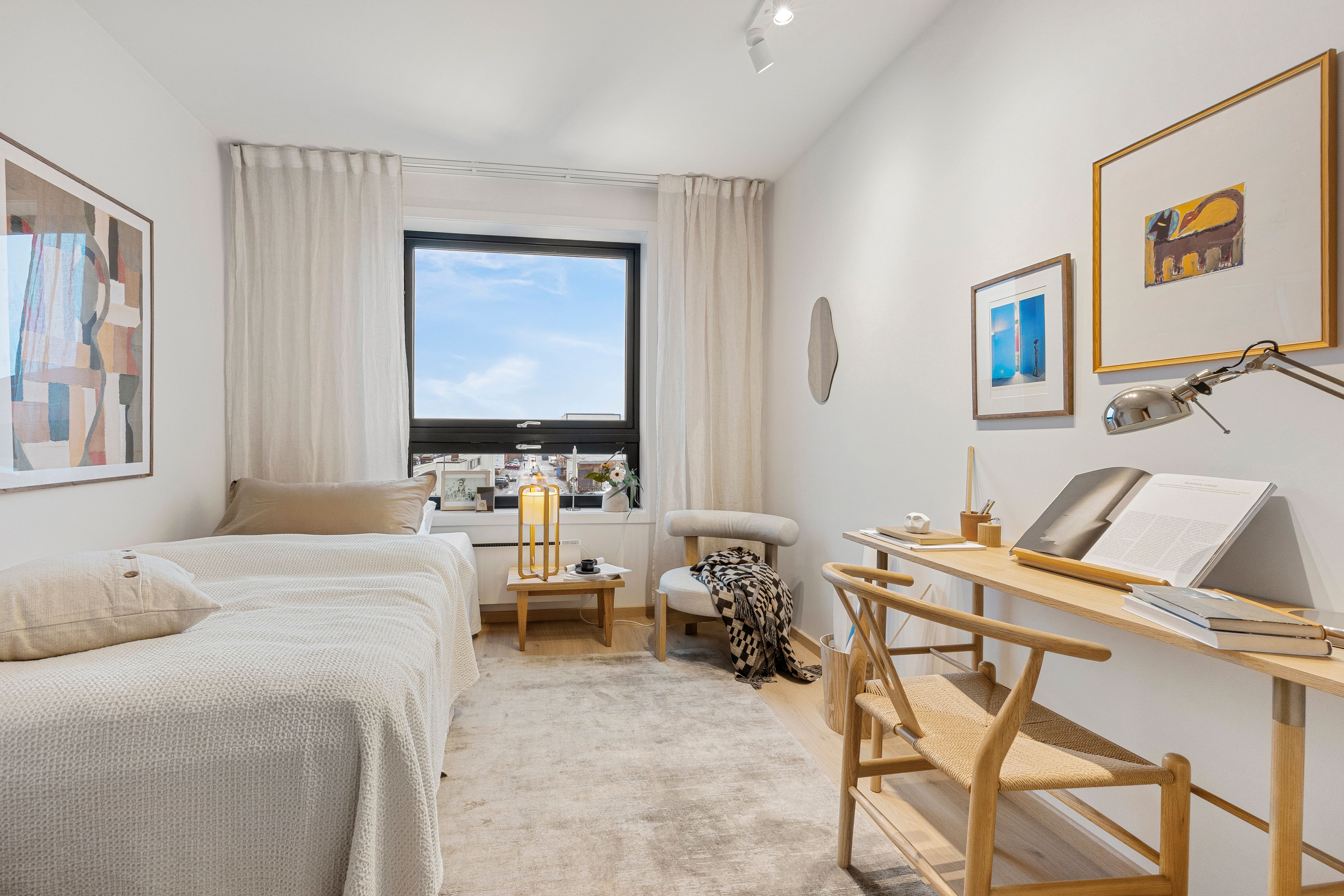 soverom med seng, stol, skrivepult og ett vindu.