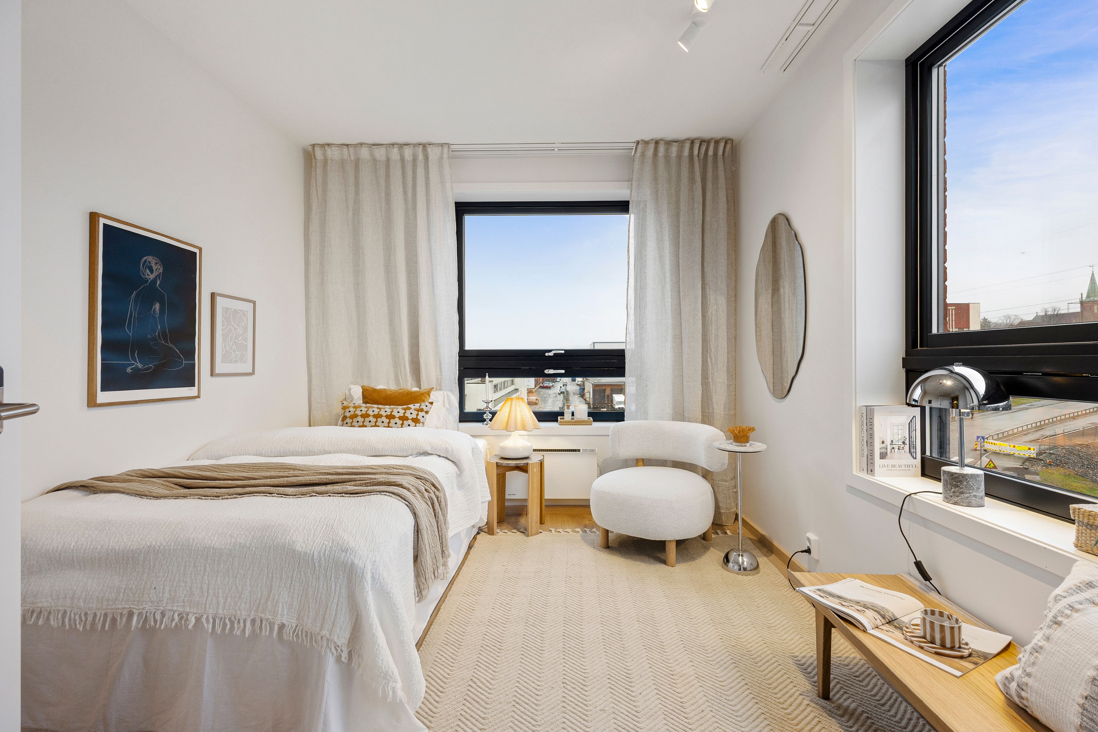 Soverom med seng og stol. To vinduer