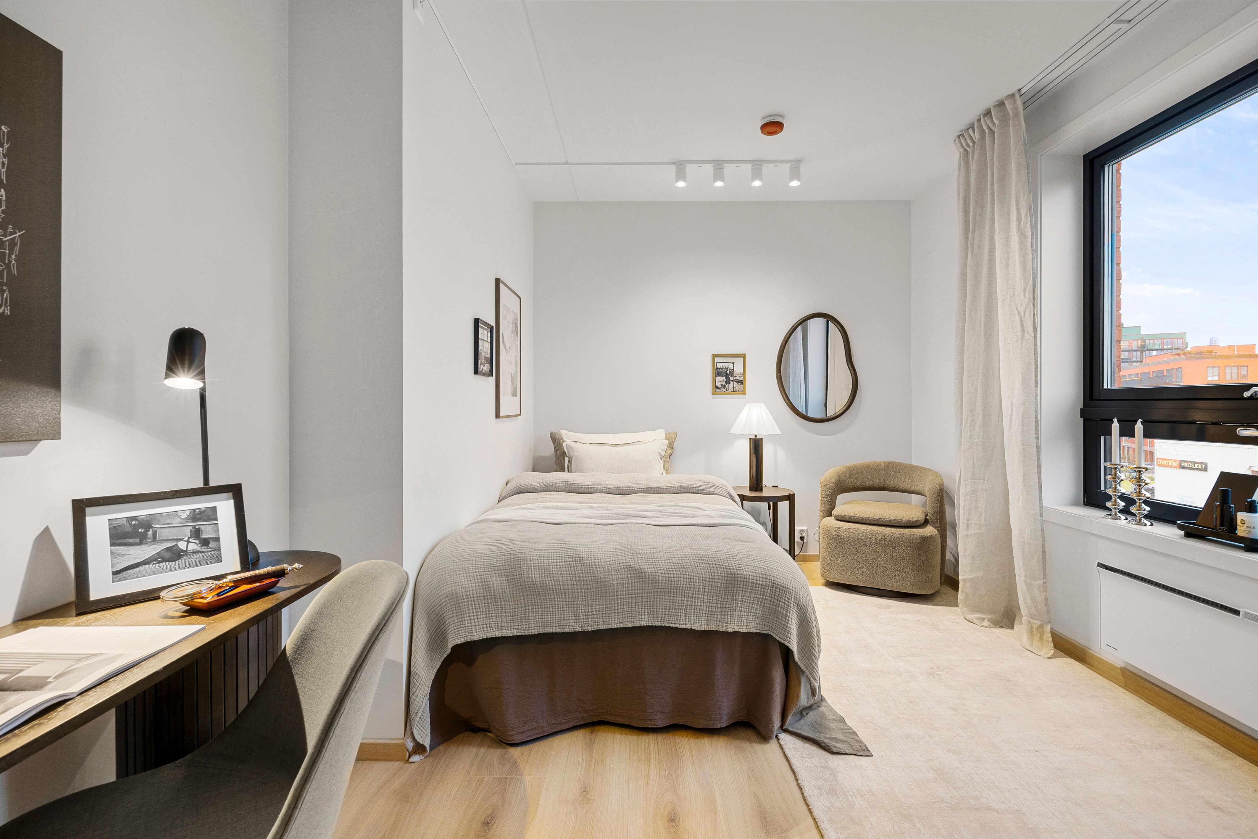 Soverom med seng, stol og skrivepult. Vindu med utsikt.