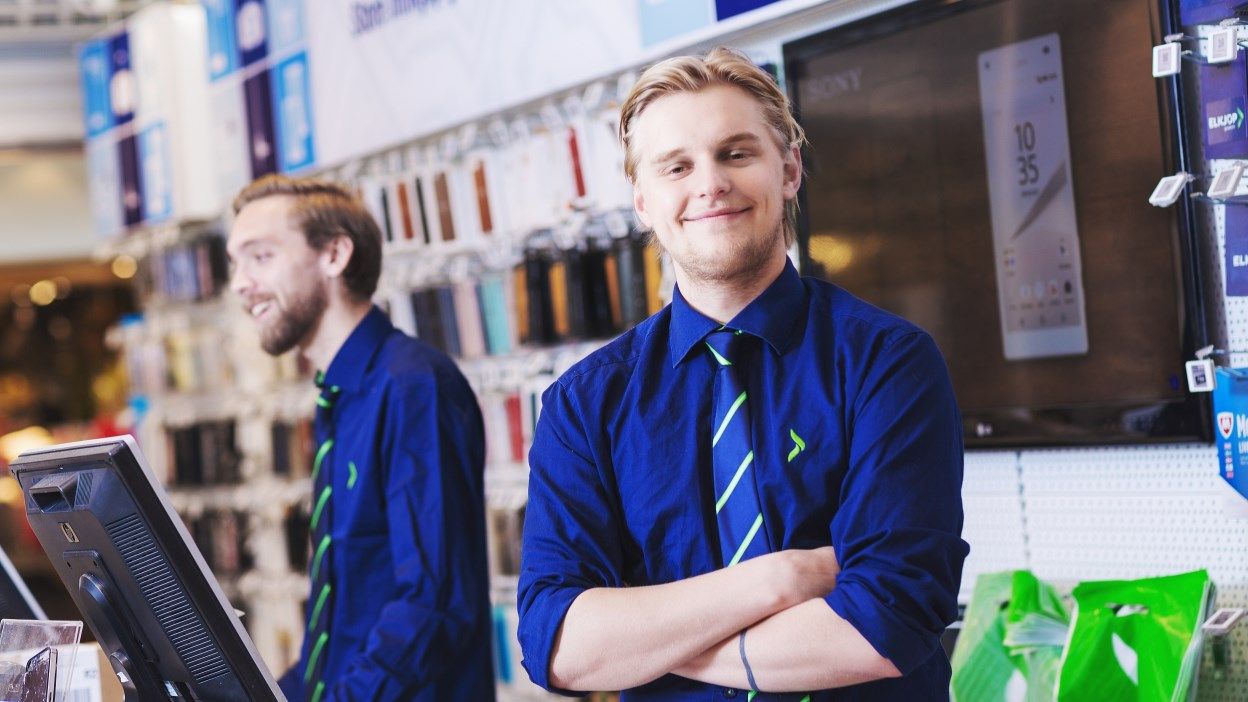 En mannlig butikkansatt smiler til kameraet. Foto.