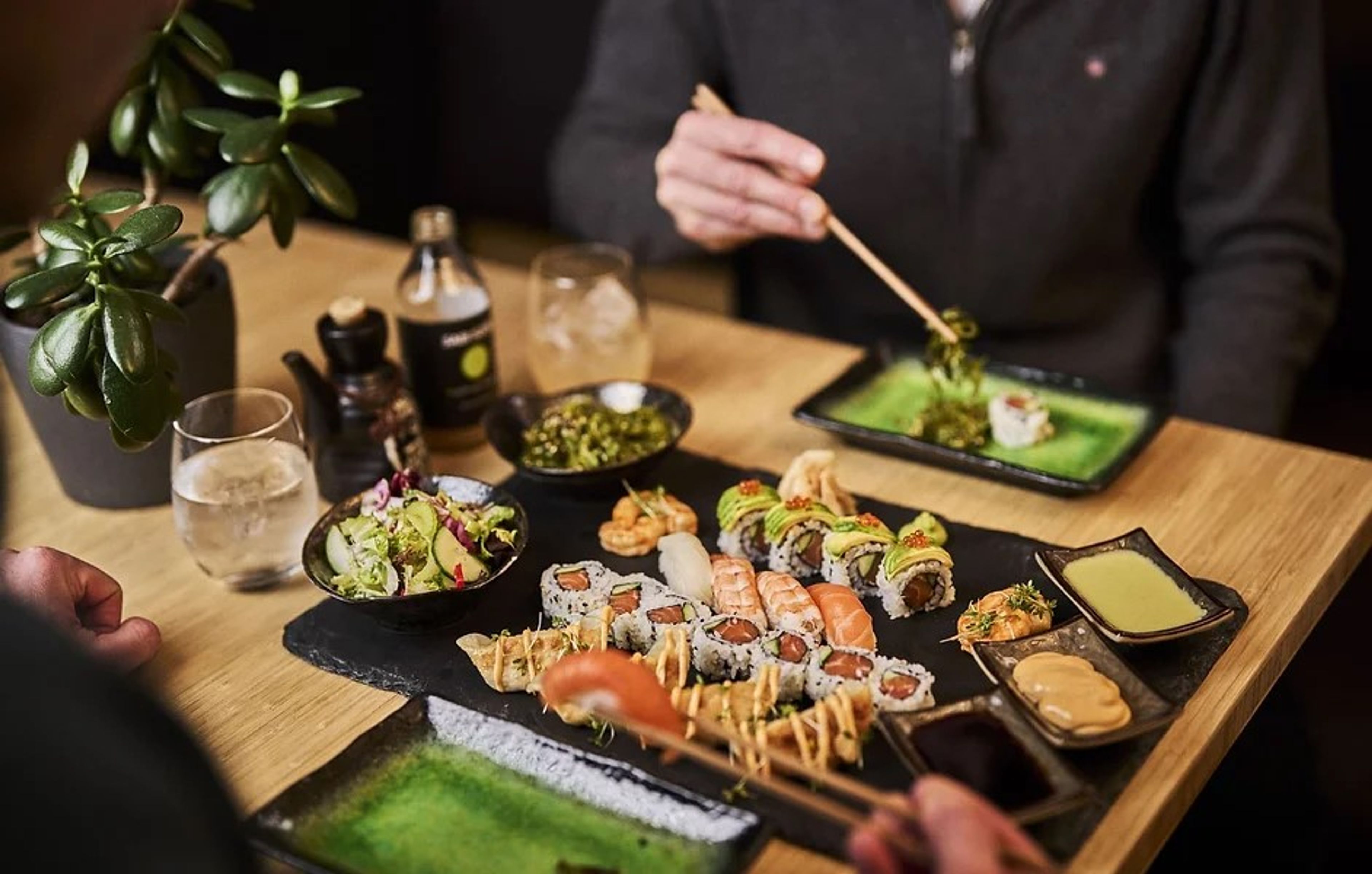 To personer  som sitter ved et bord og spiser ulike typer sushi