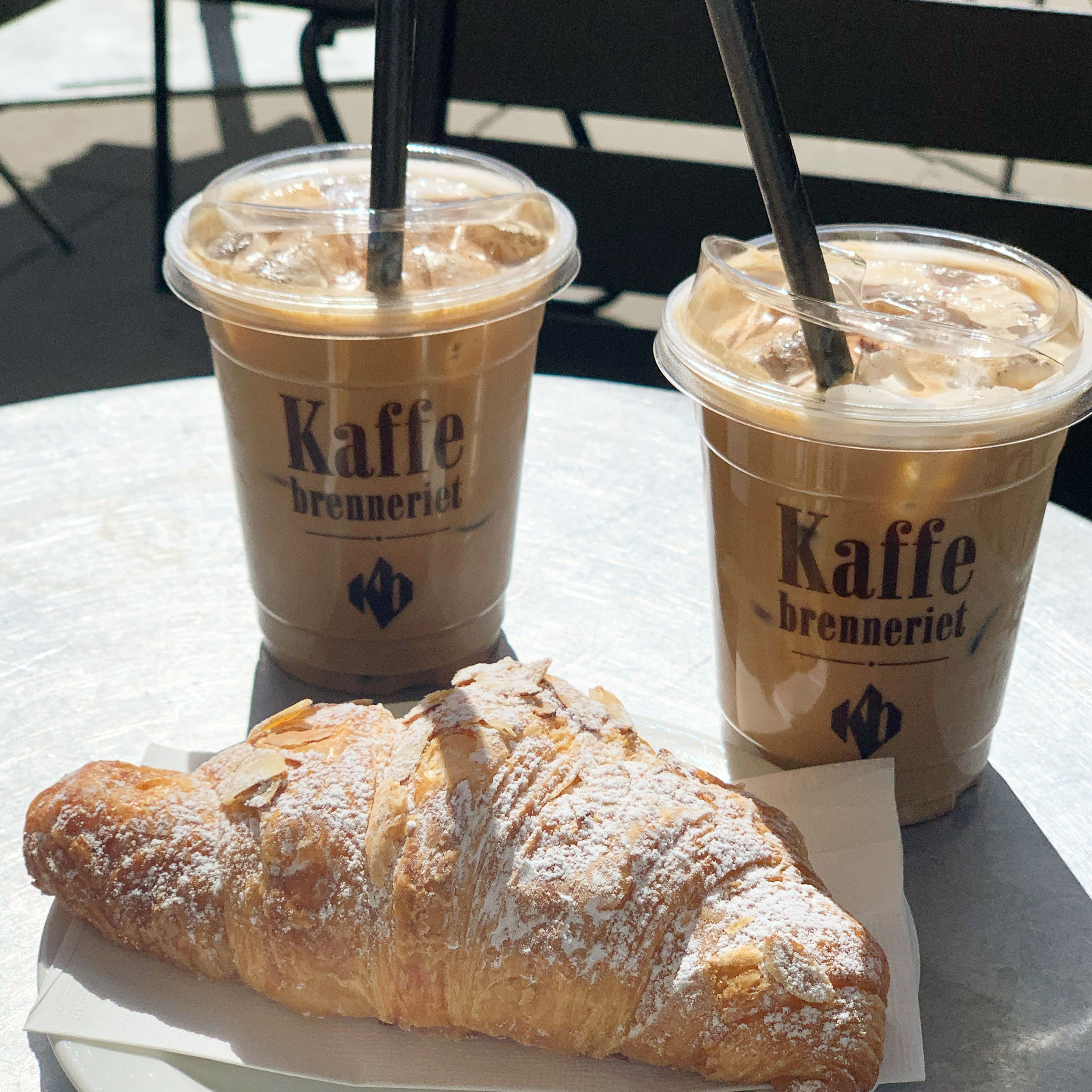 Foto av to kopper med kaffe og en croissant.