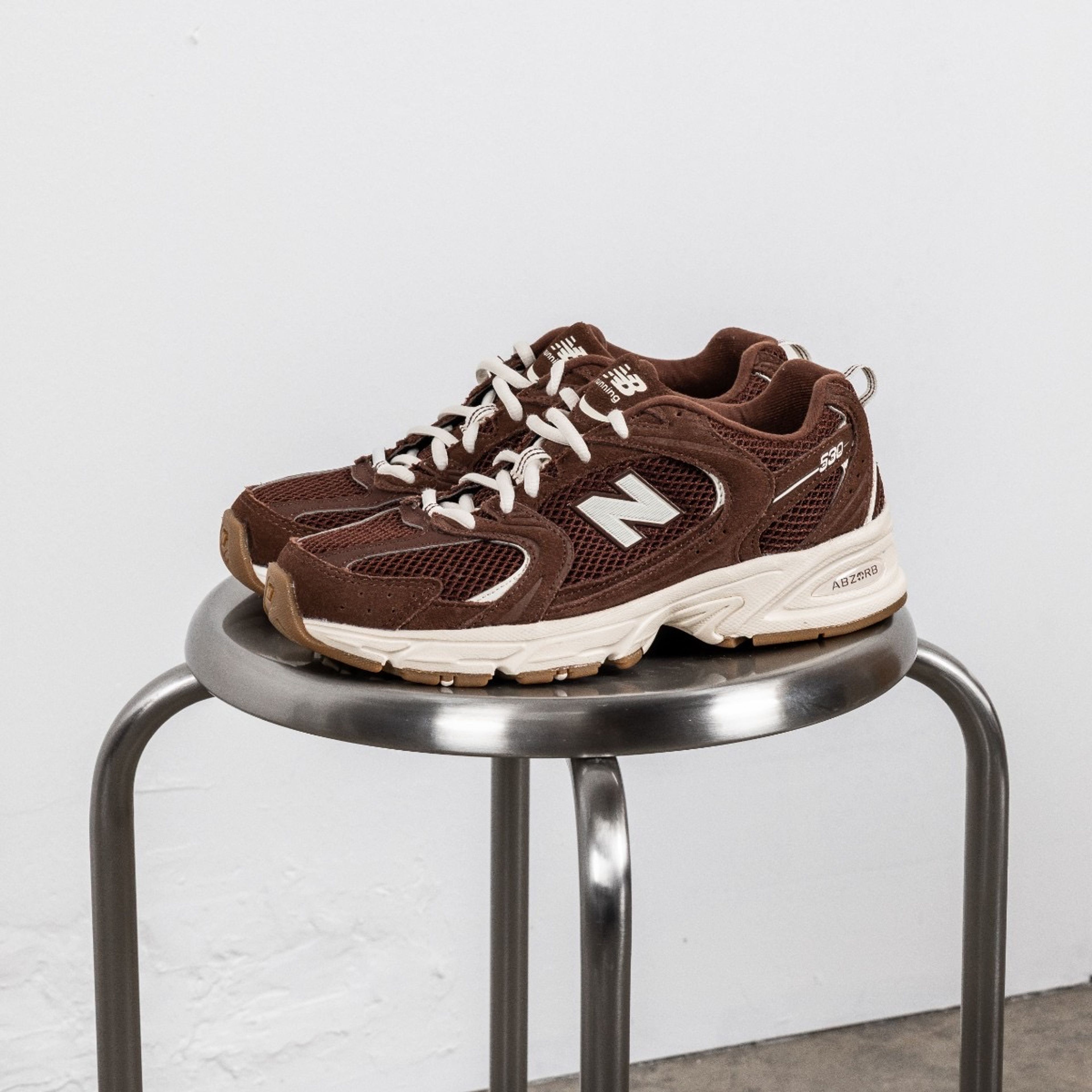 Et par New Balance sko, plassert på en sølv stol.