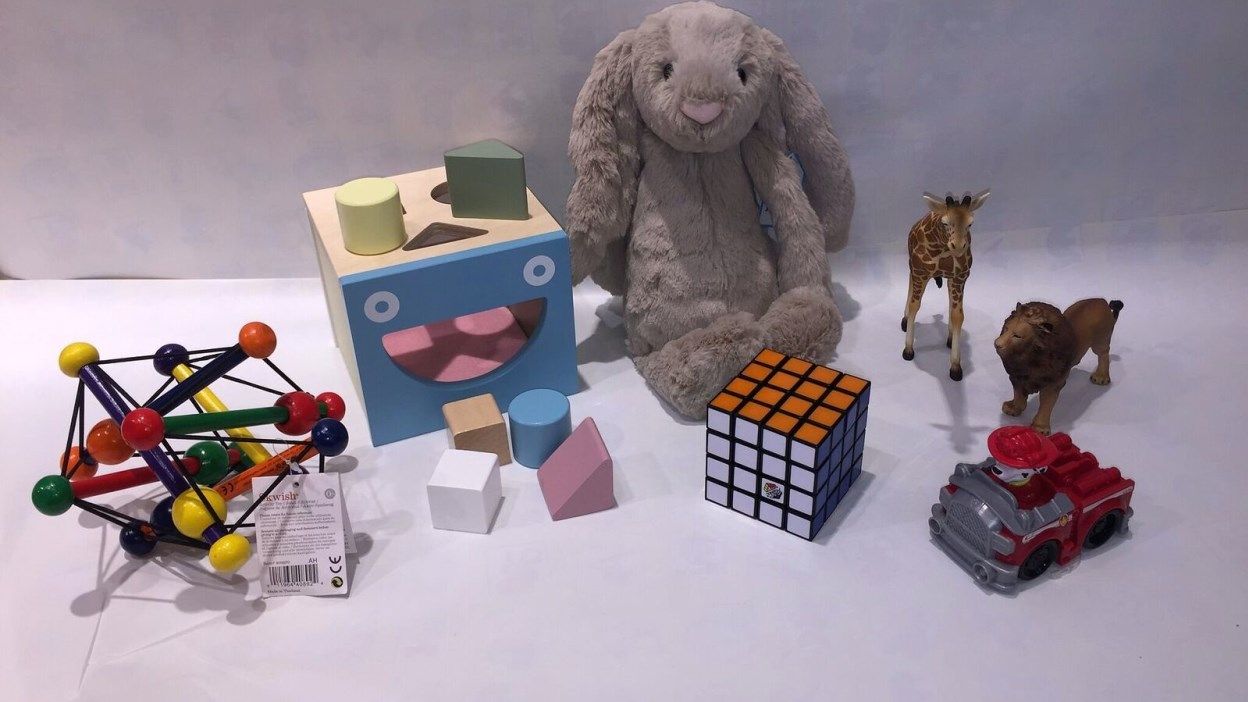 Bilde av barneleker, kaninbamse, rubixkube, lekedyr og puttekasse.