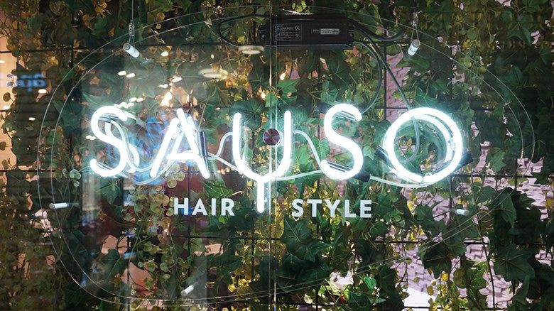 Grønn blomstervegg med teksten sayso hair style i lysende bokstaver