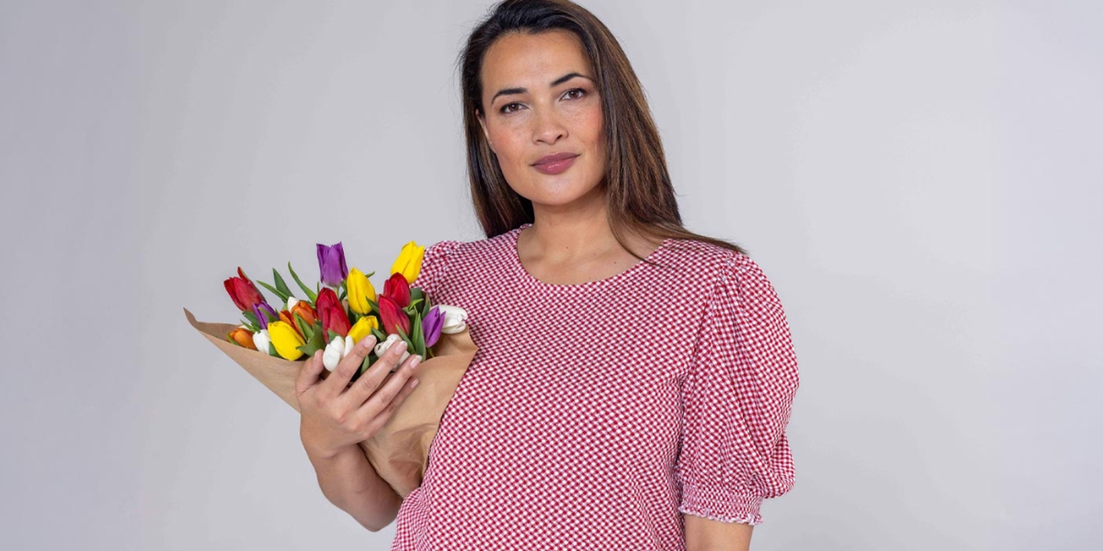 En dame med rosa bluse som holder en bukett tulipaner.