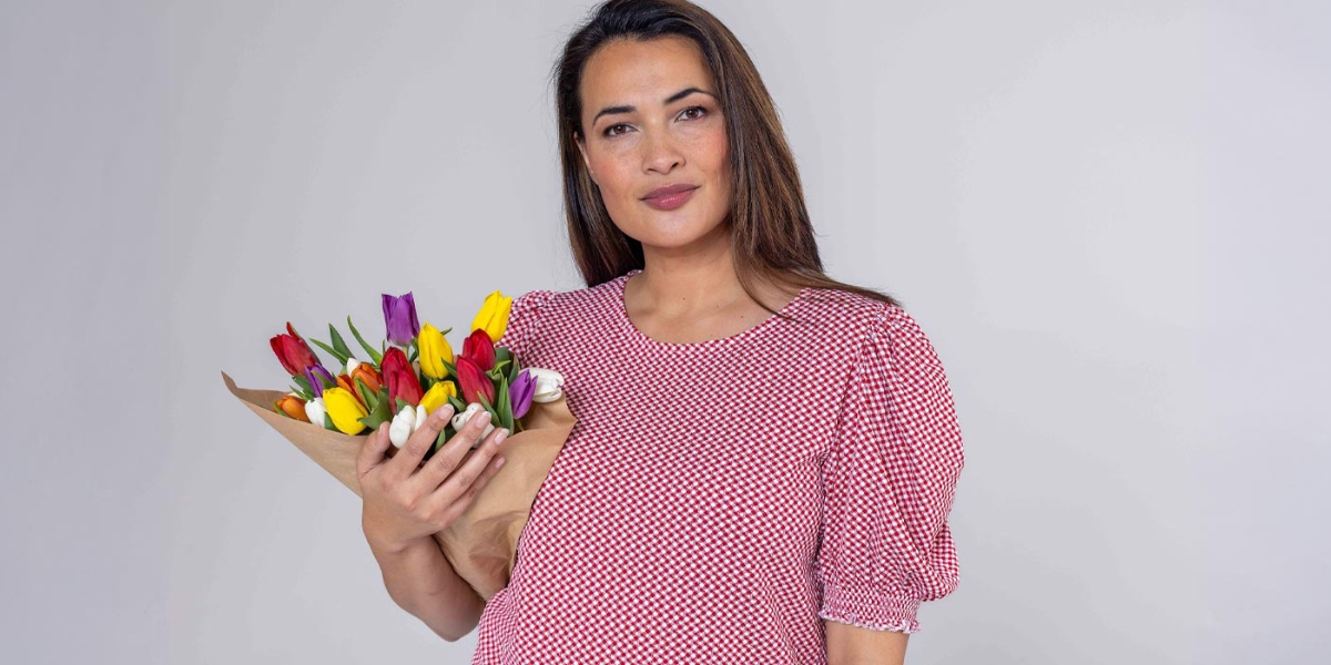 En dame med rosa bluse som holder en bukett tulipaner.