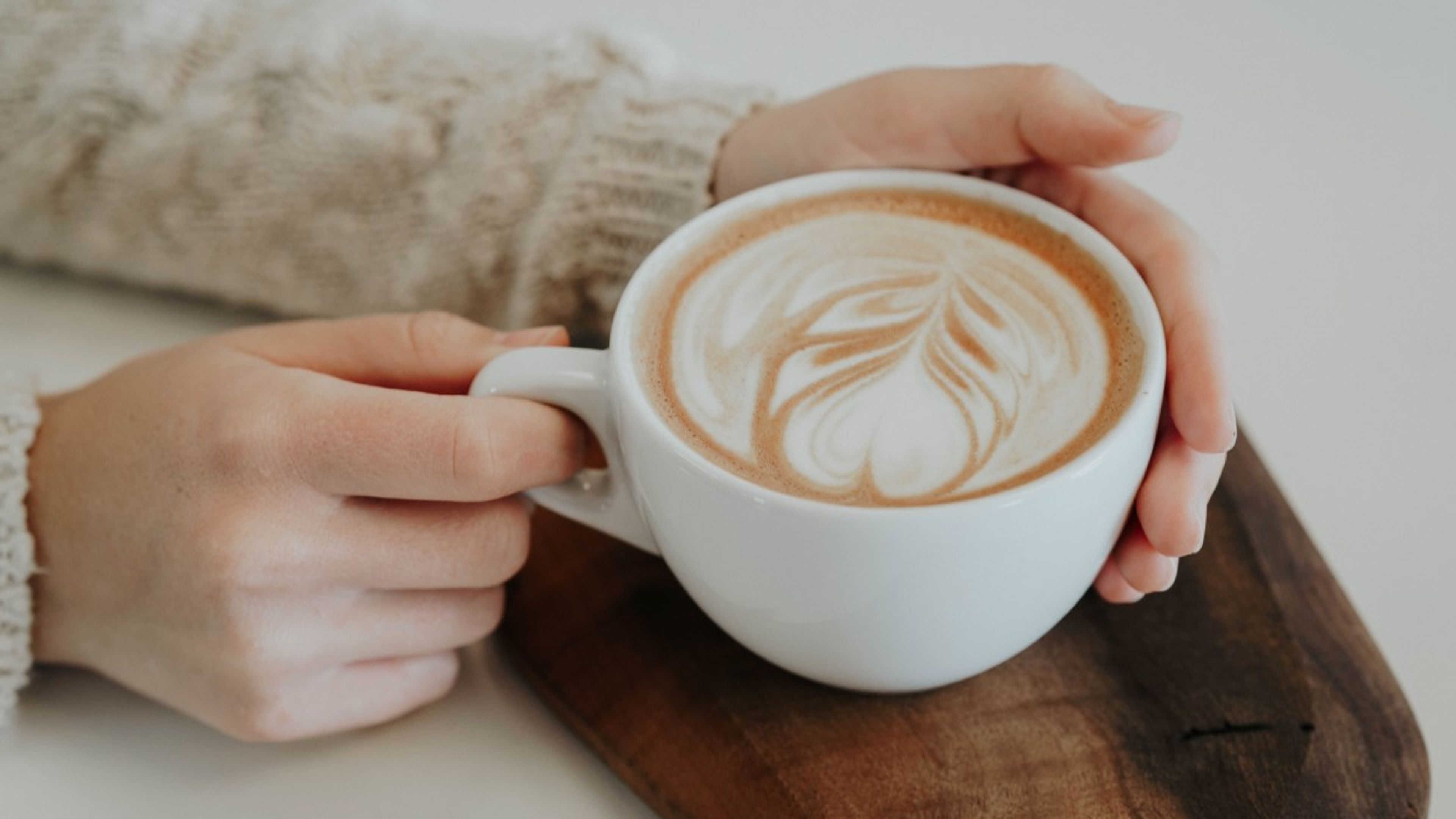 To hender holdt rundt en kopp med kaffe. Foto.