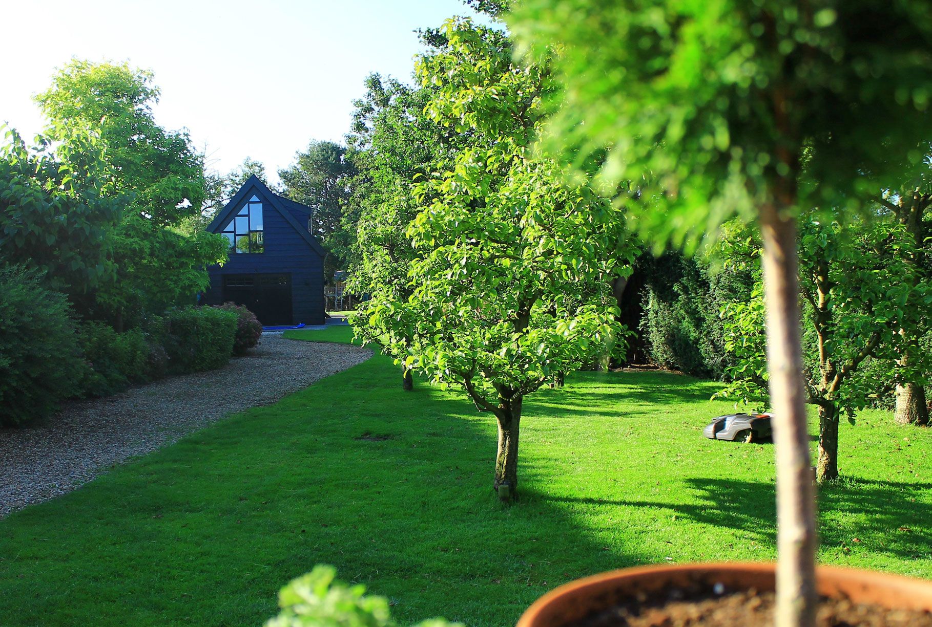 Bilde av et hus med stor hage med trær og gressplen