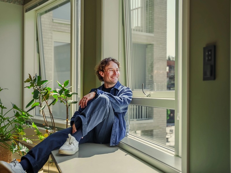 En mann som sitter i vinduskarmen og ser utover