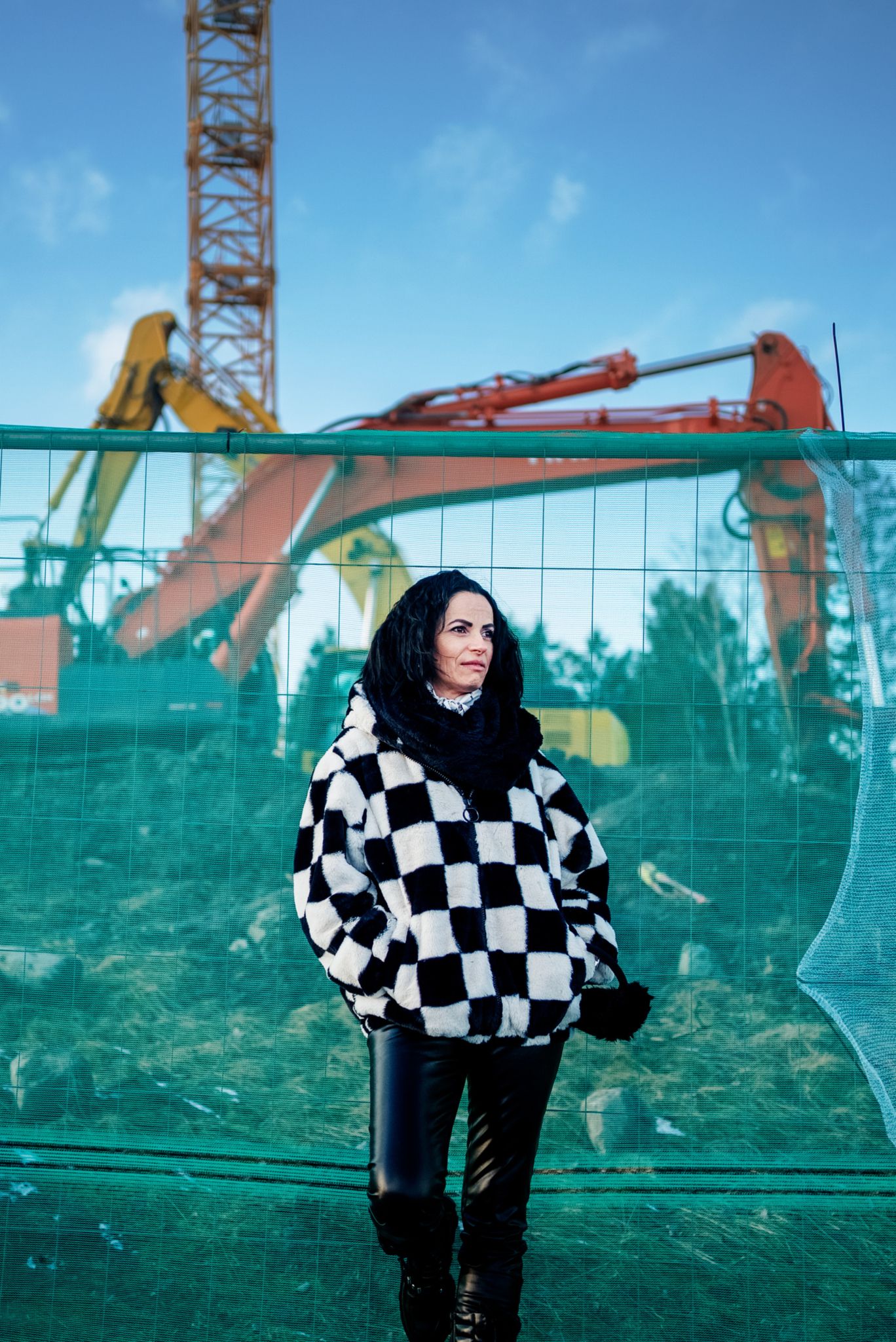 Mihaela står foran gjerdet til en byggeplass.