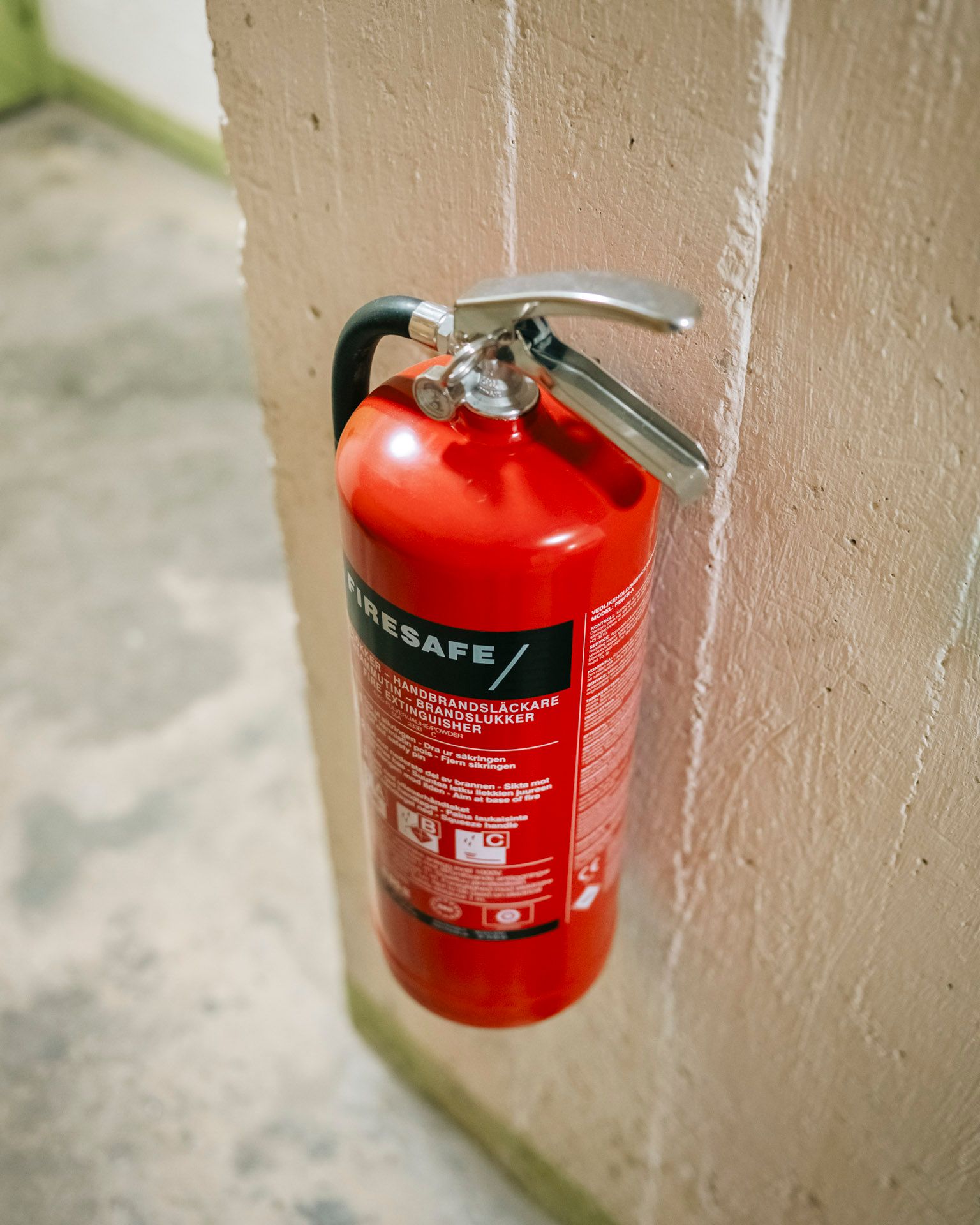 Rød brannslokker merket Firesafe montert på en beige vegg ved Gjøvikgata borettslag, Oslo.