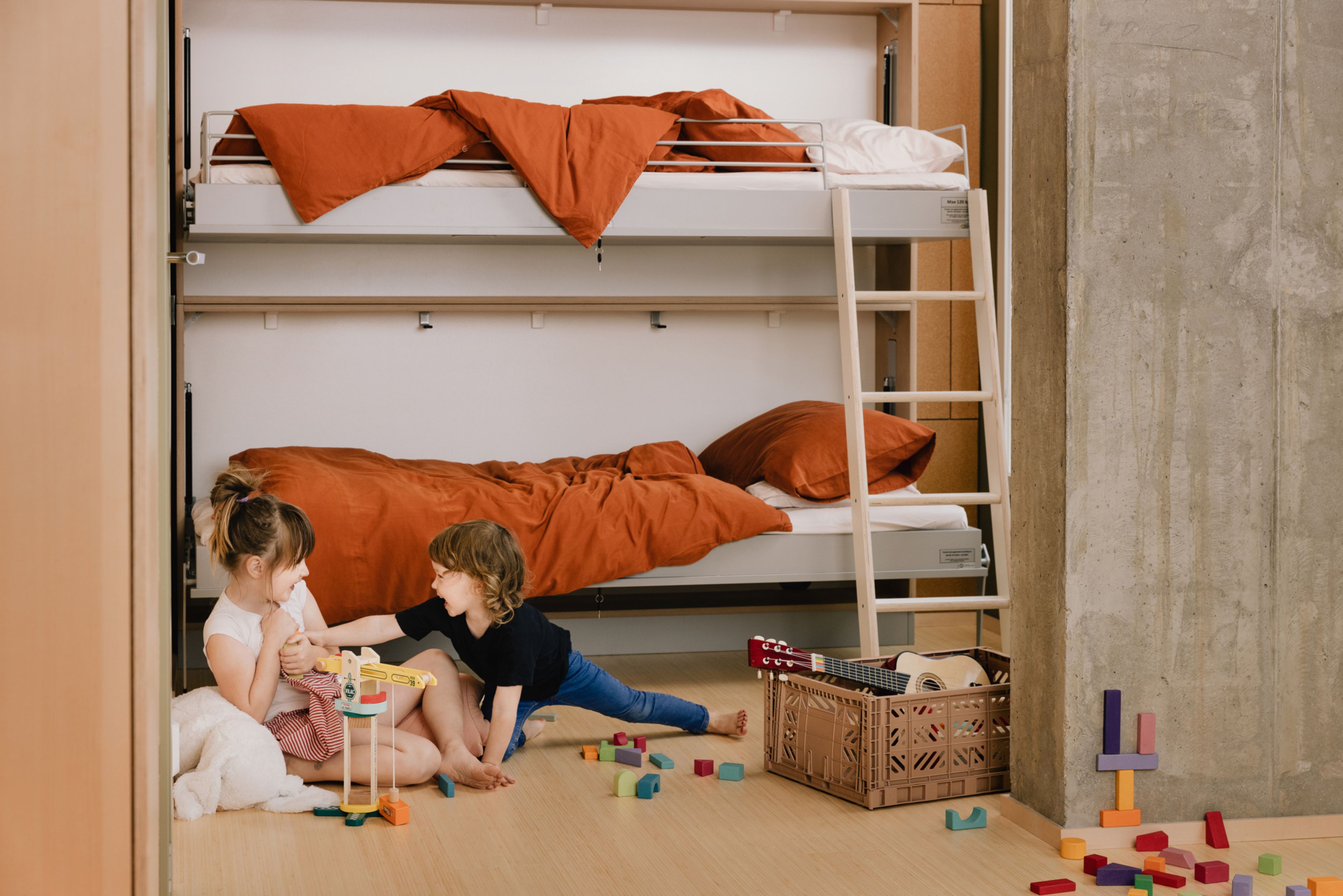 Foto av to barn som leker på gulvet på et barnerom i OBOS Living Lab