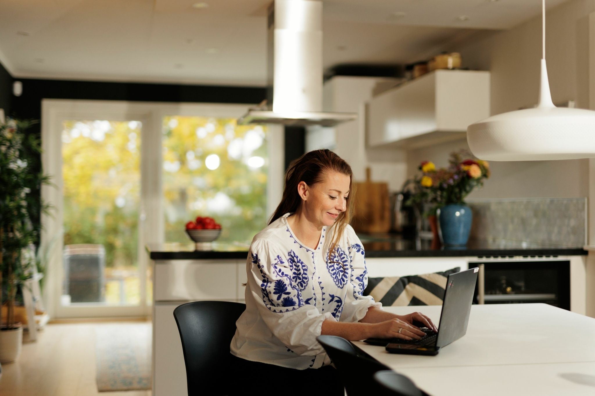 Portrett av Silje Strand Ekelund, leder for personmarked i OBOS-banken, som sitter hjemme med PC-en sin ved kjøkkenbordet.