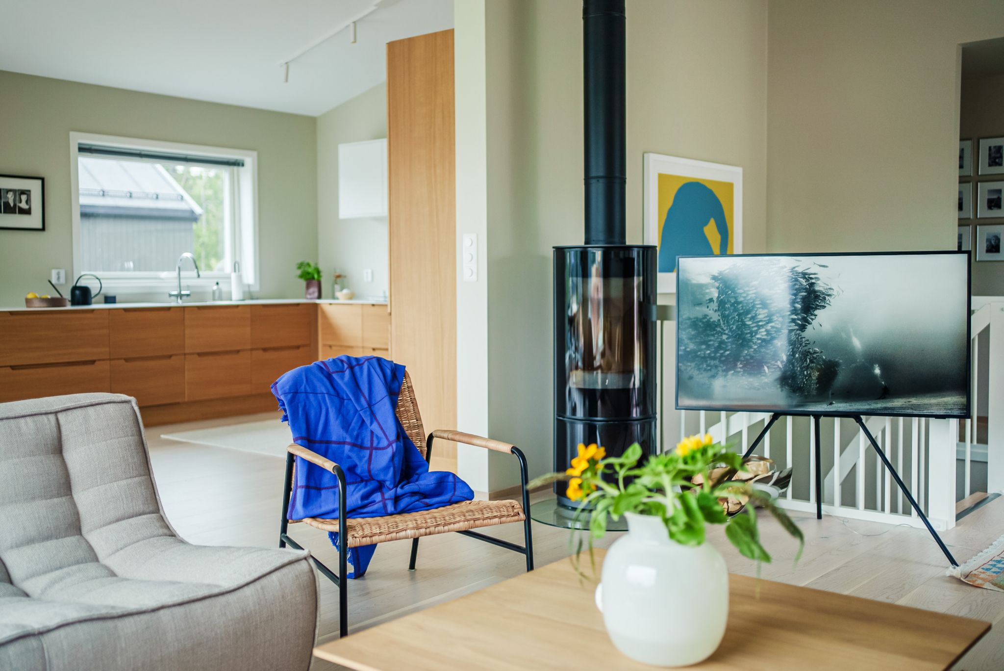 Stue med sofa, sofabord, lenestol, tv og peis. Kjøkken i bakgrunnen.