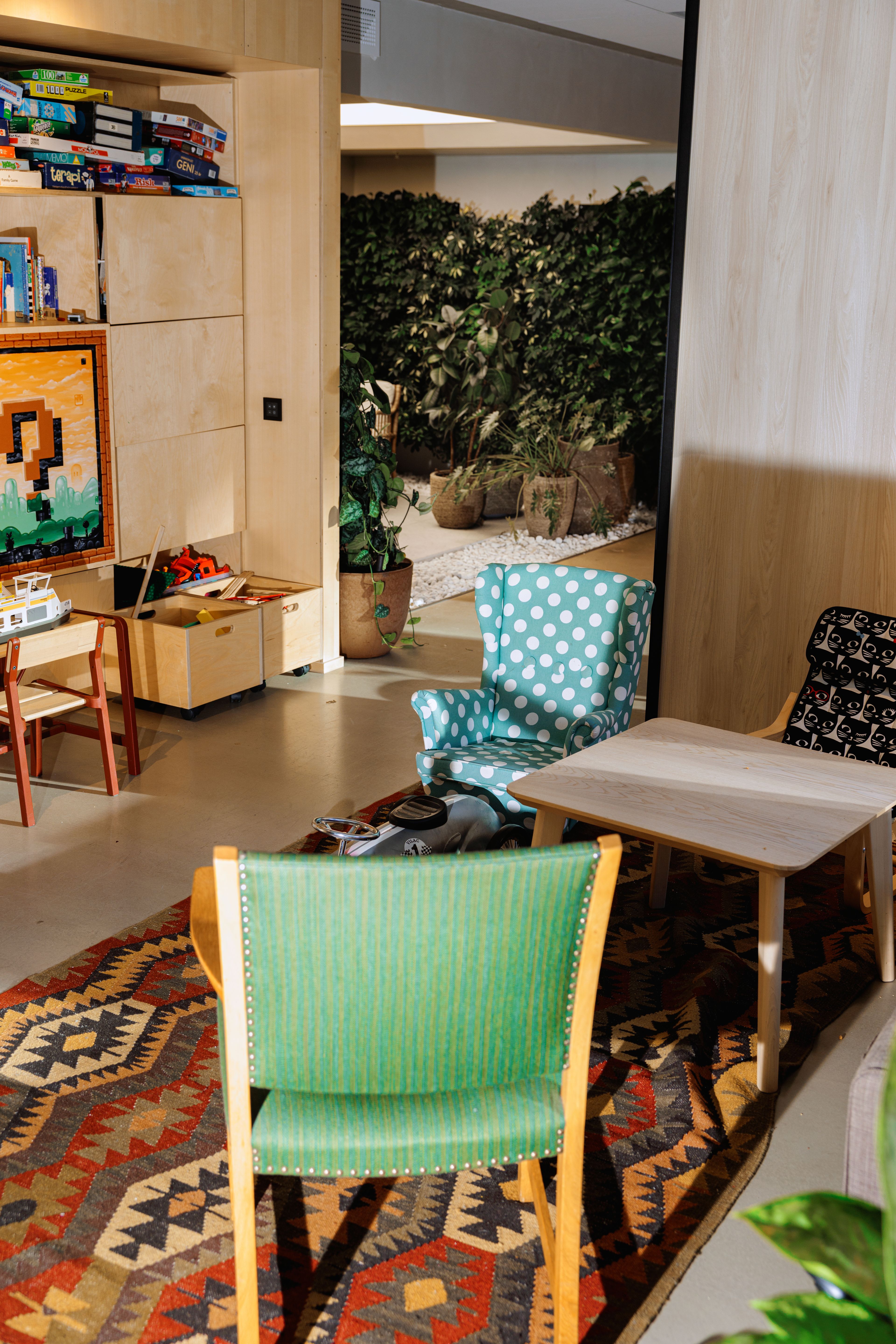 Et fellesrom med fargerike møbler og en hylle fylt med spill og leker. 