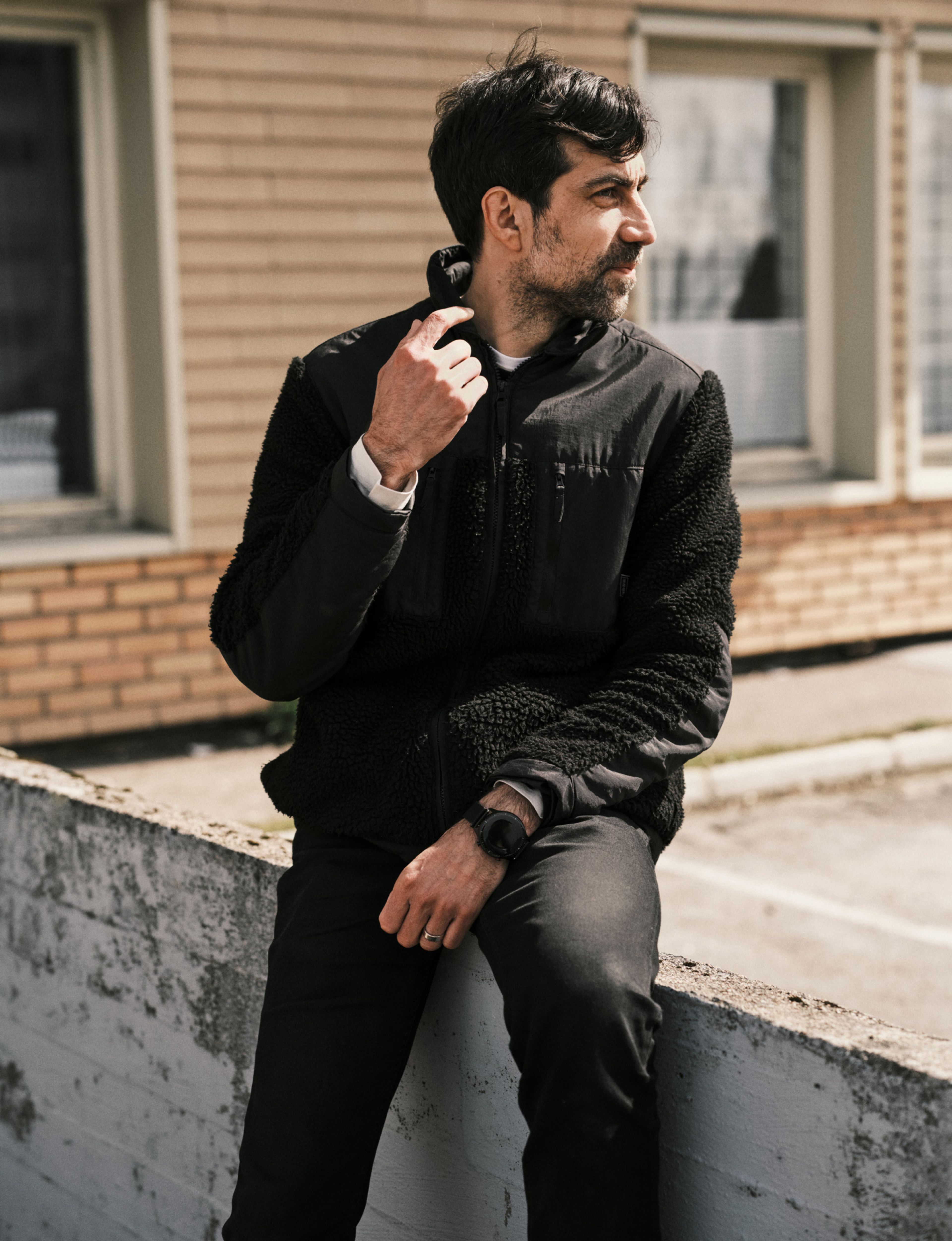 Zeshan Shakar sitter på en betongblokk og ser mot den ene siden.
