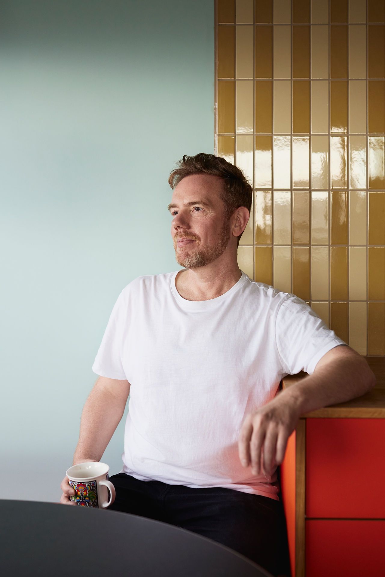 Bilde av Lars som sitter ved spisebordet med en kaffekopp i hånda.