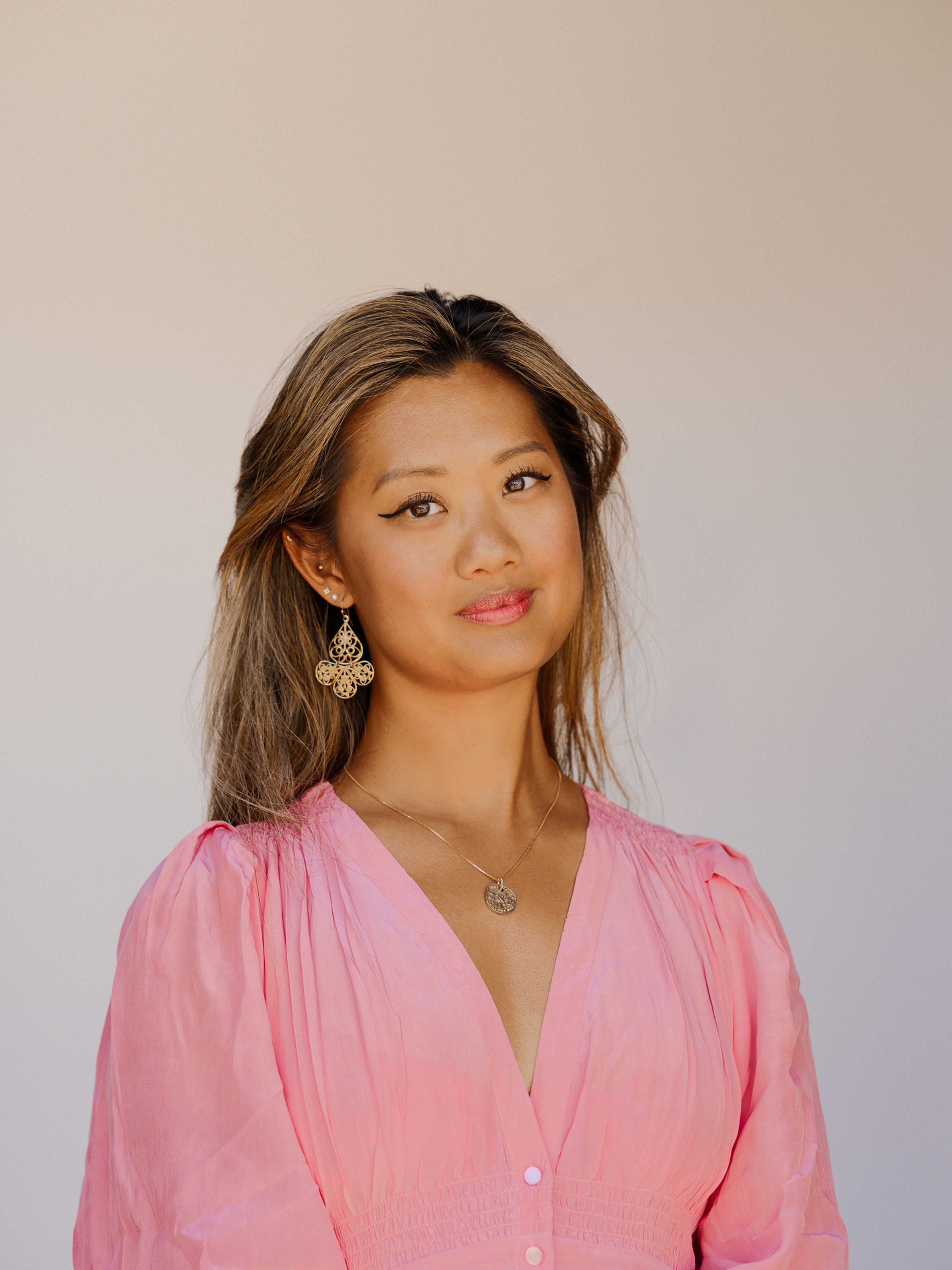 Catharina Chen står inntil en hvit vegg og har på seg en rosa kjole.