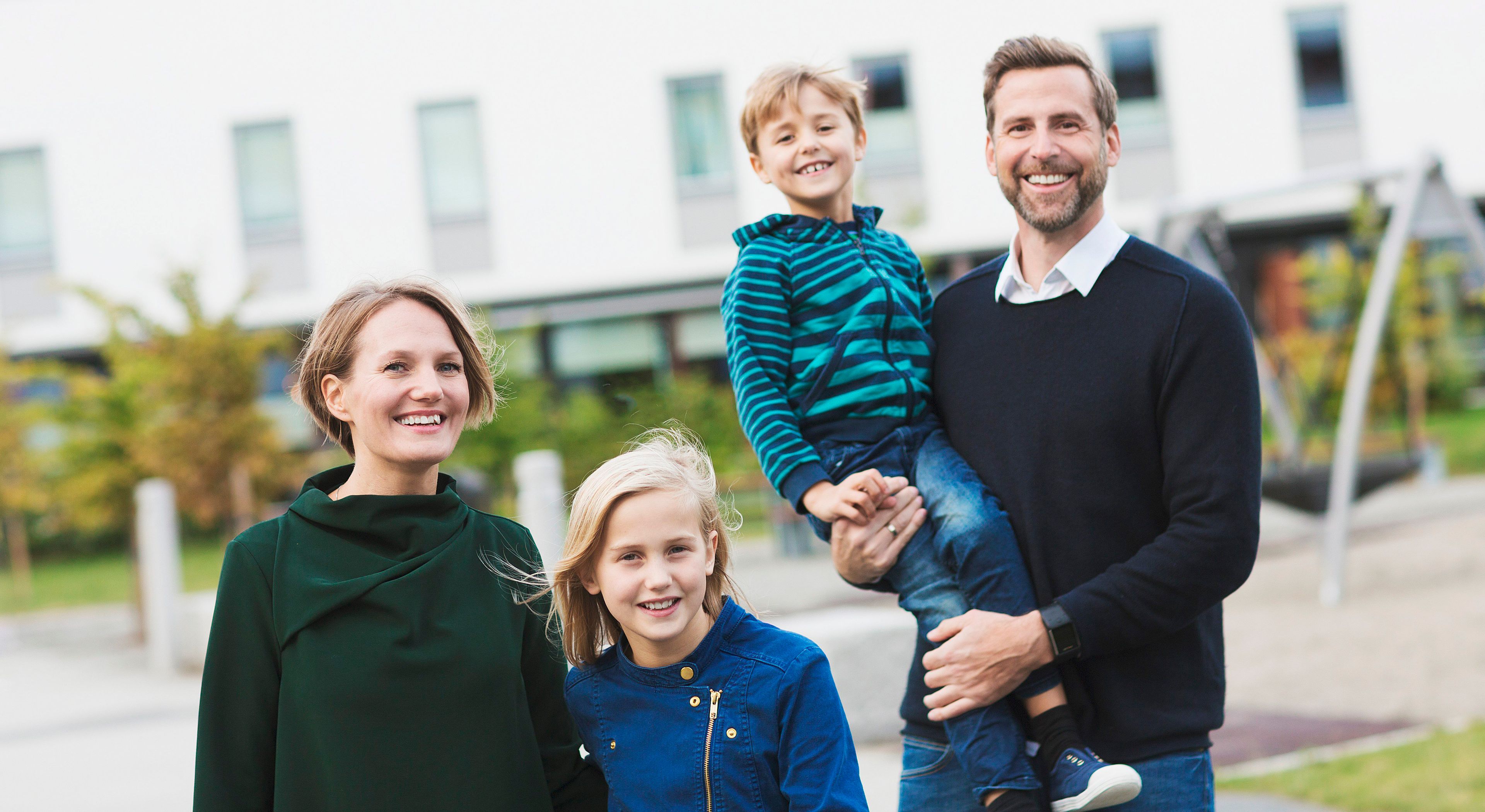 Bilde av familie med mor, far og to barn i en bakgård på Fornebu.