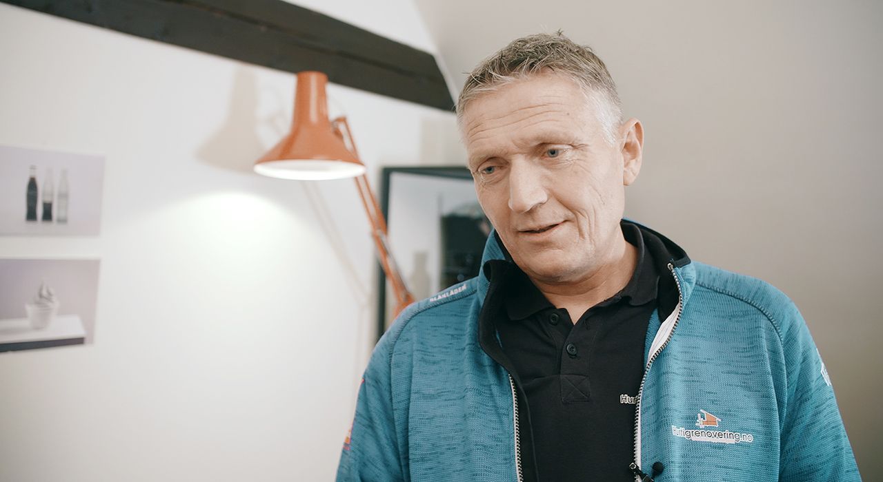 en mann står i en stue med en lampe i bakgrunnen