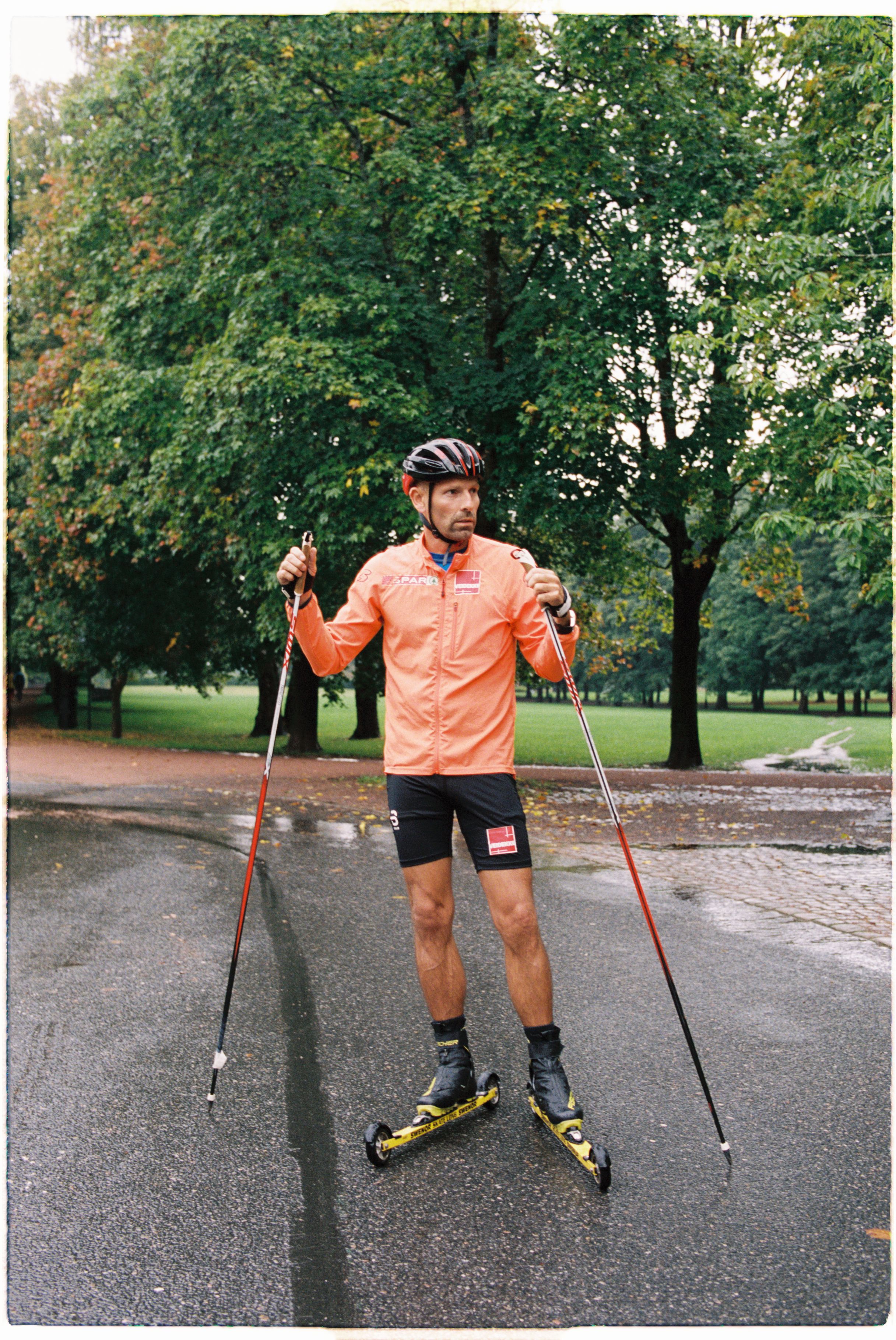Jonas Kinge Bergland har på seg oransje treningstøy, har en hjelm på hodet og rulleski på beina.