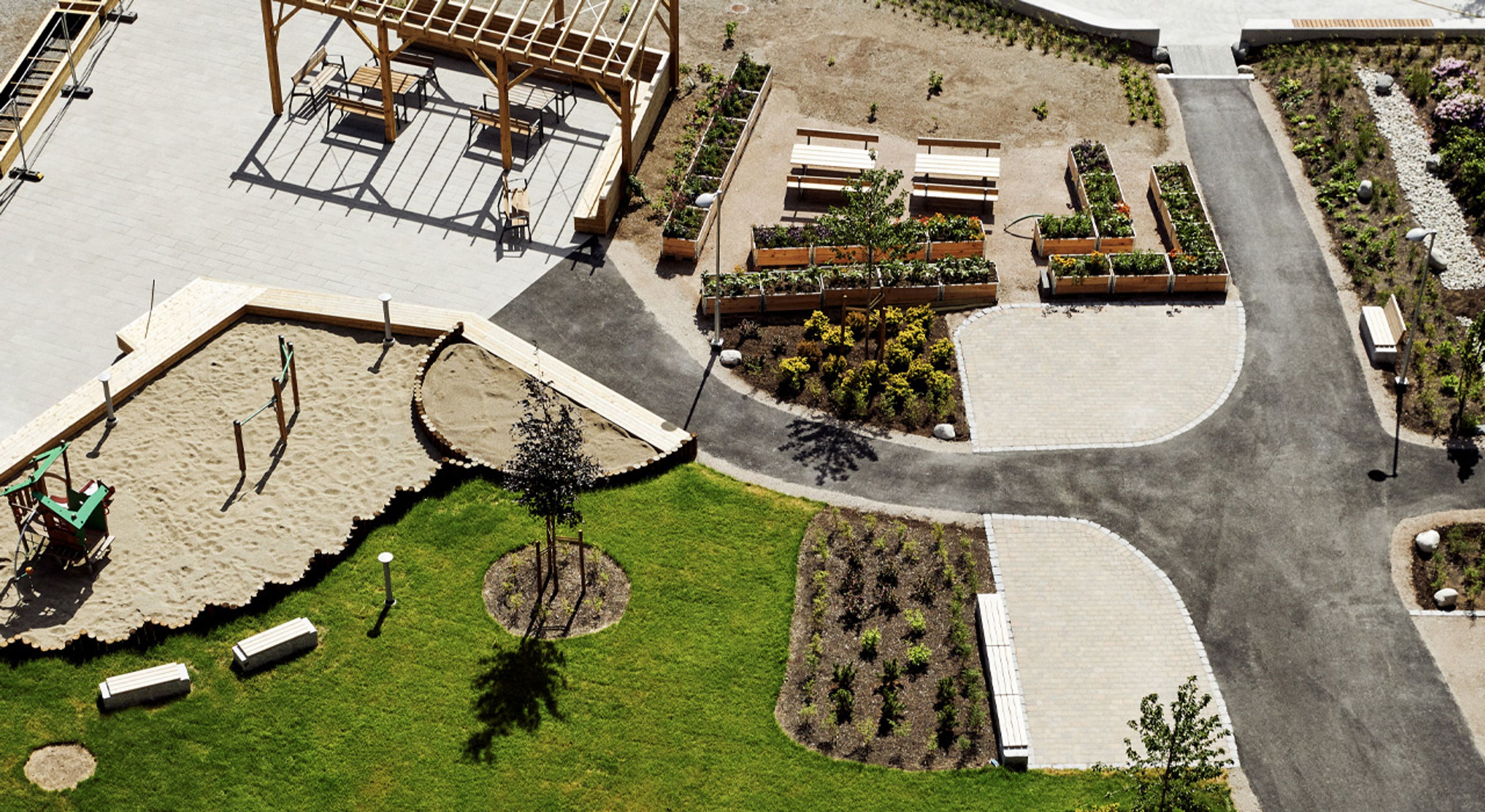 Dronebilde av uteområdene på Ulven med pergola, lekeplass og plen.