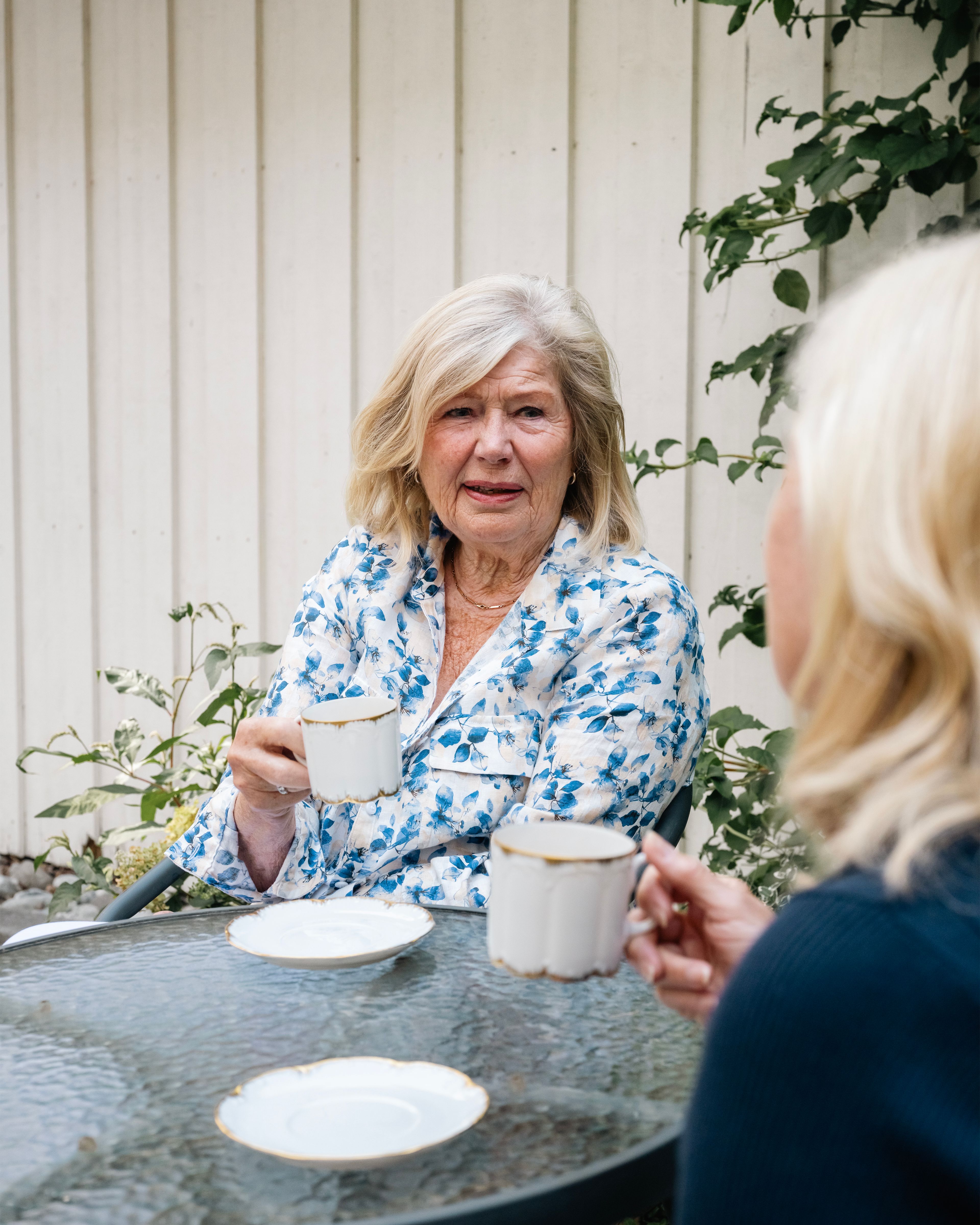 To damer sitter ute med hver sin kaffekopp. De skravler.