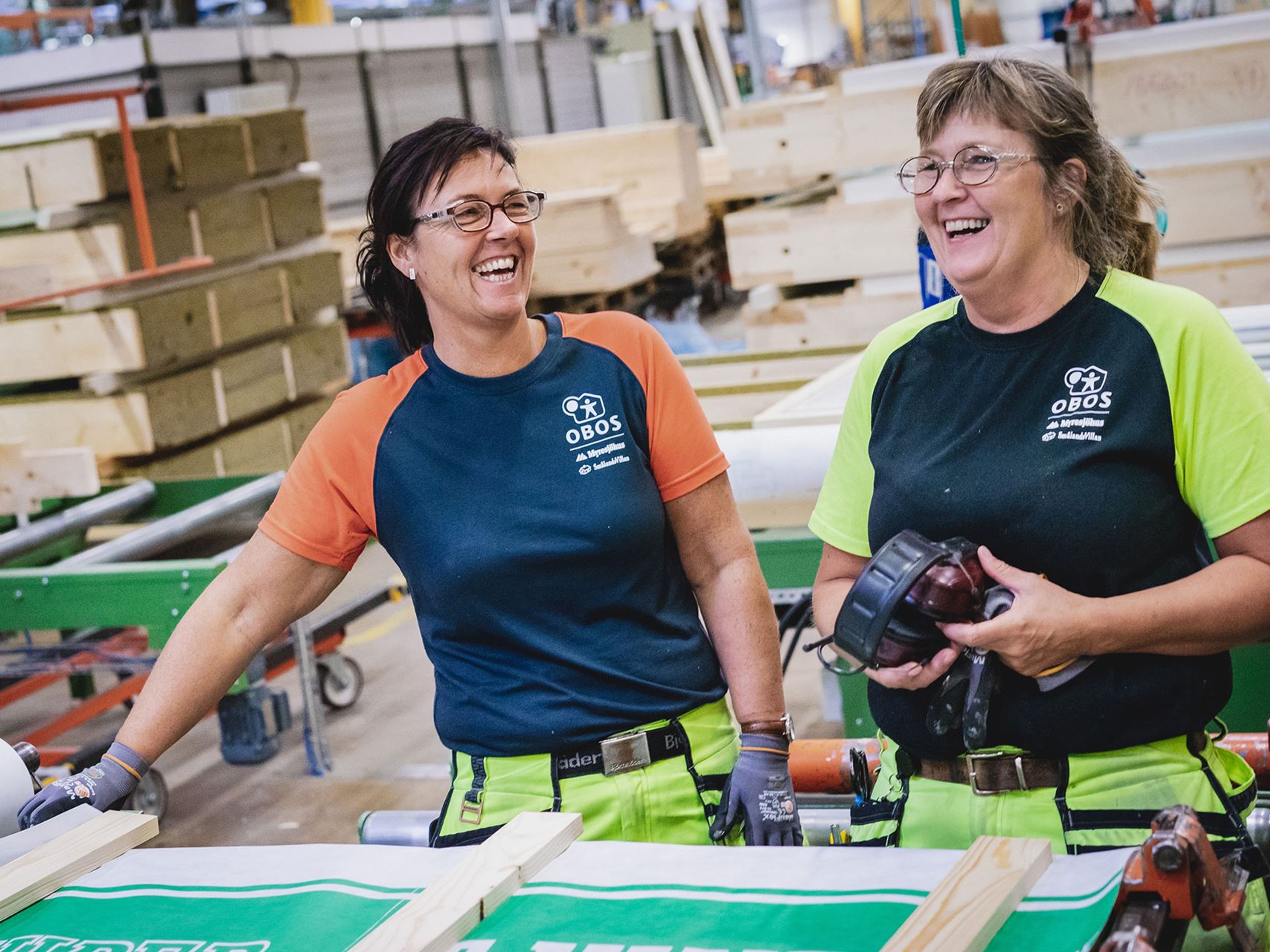 Två skrattande damer som arbetar på en obos fabrik