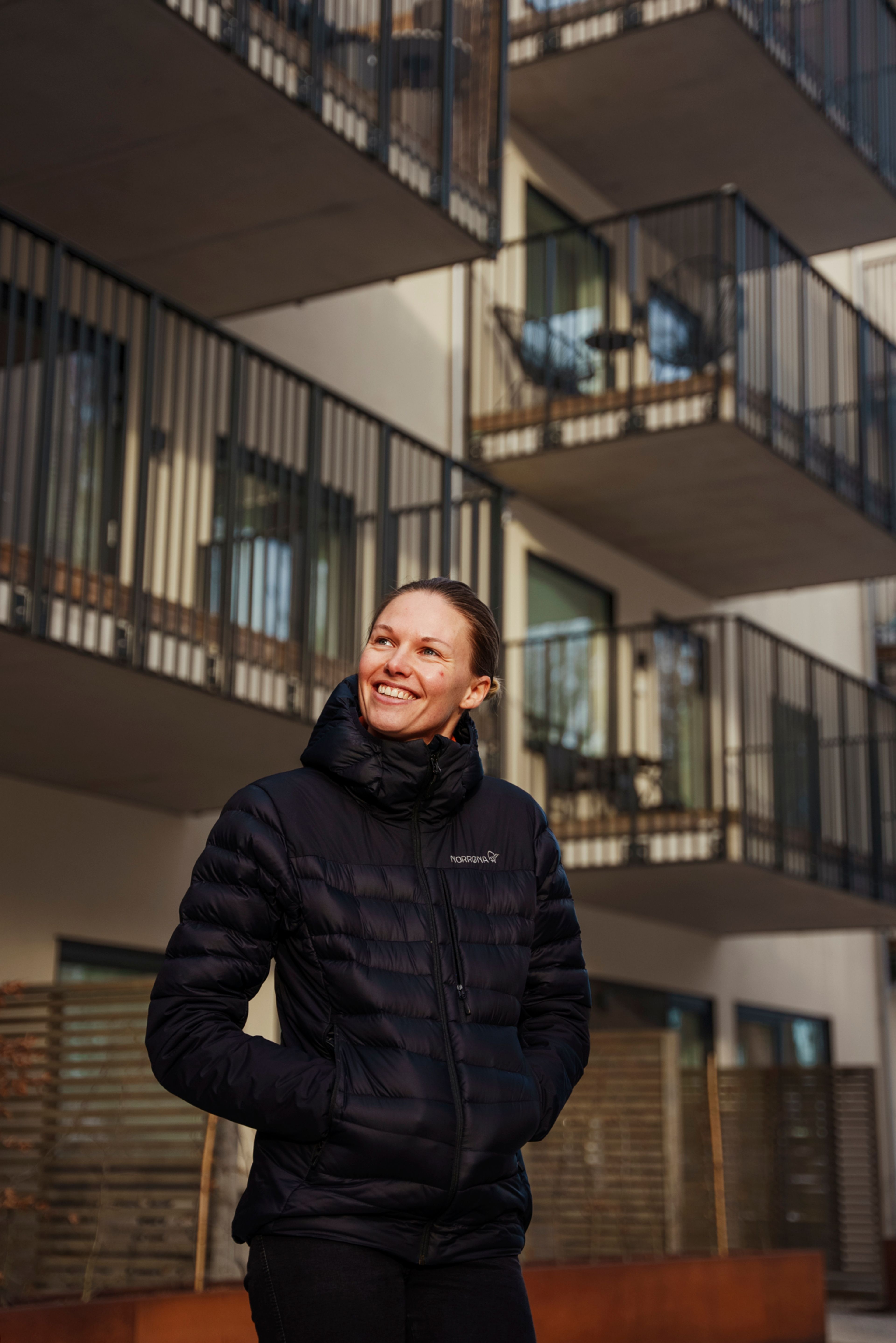 Martine smiler i bakgården i Teieparken med fasadene i bakgrunnen.