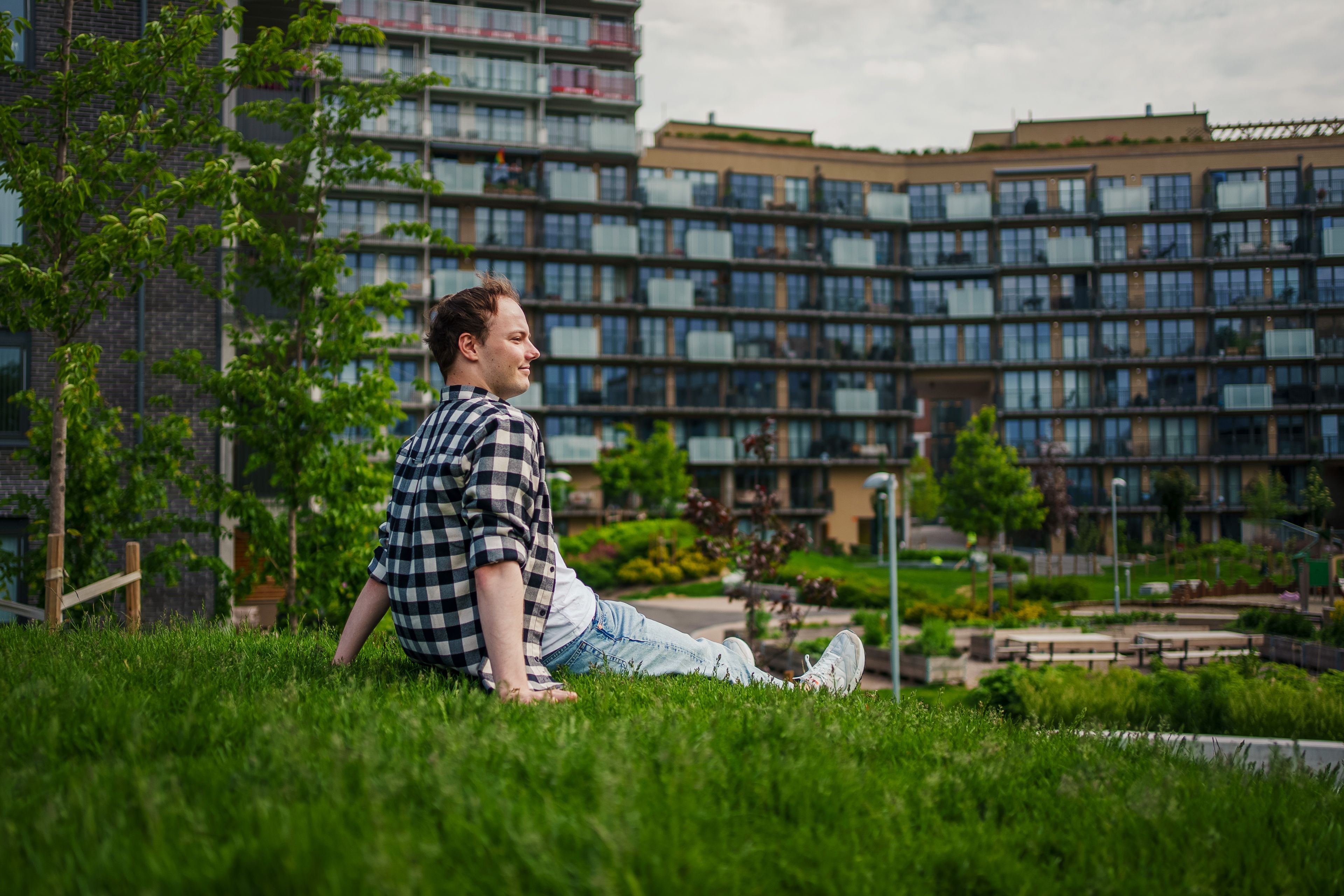 Fotografi av Sander som sitter på gresset på uteområdet på Ulven