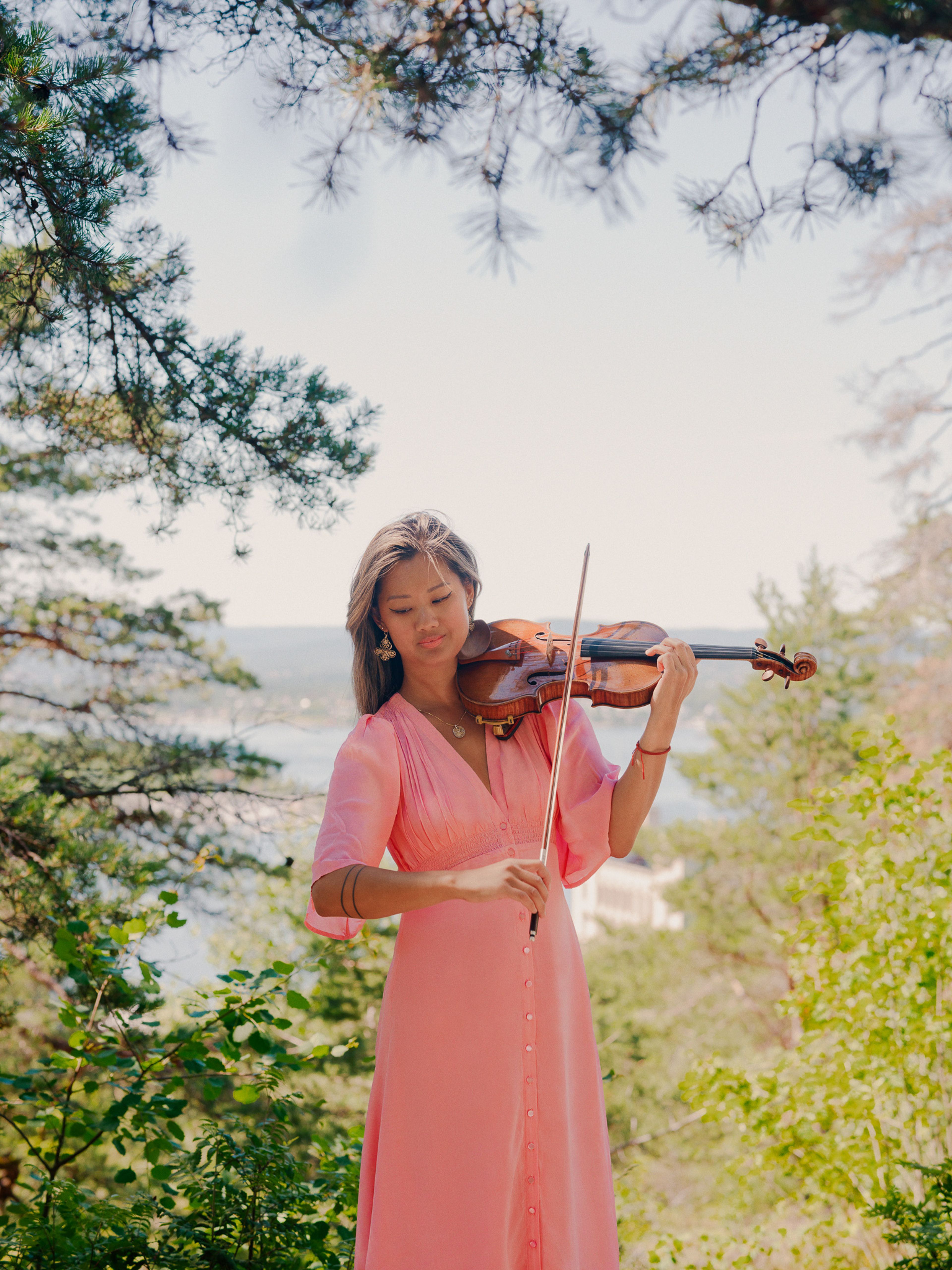 Catharina Chen spiller på fiolinen sin ute i skogen.