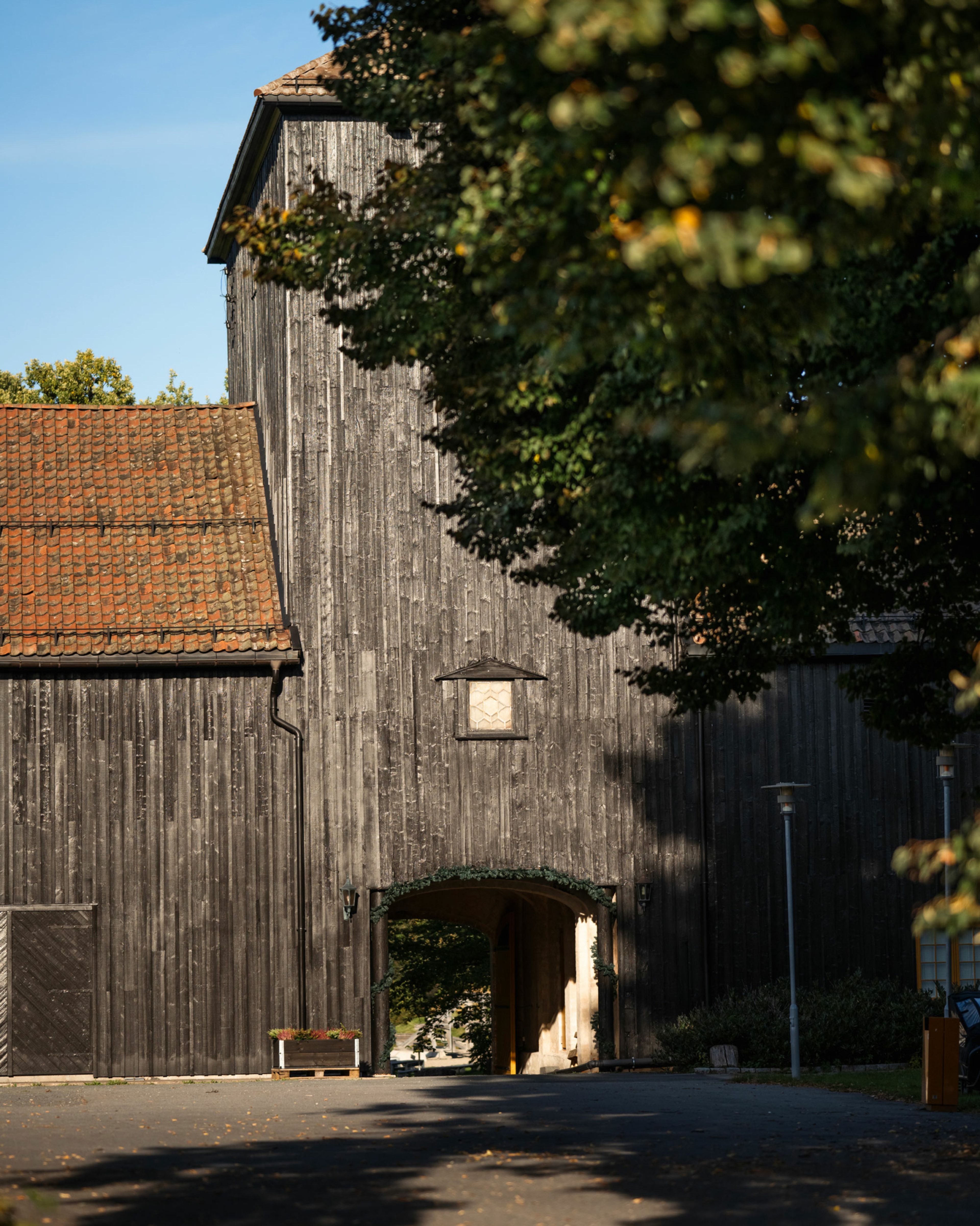 En svart bygning bak et stort tre.