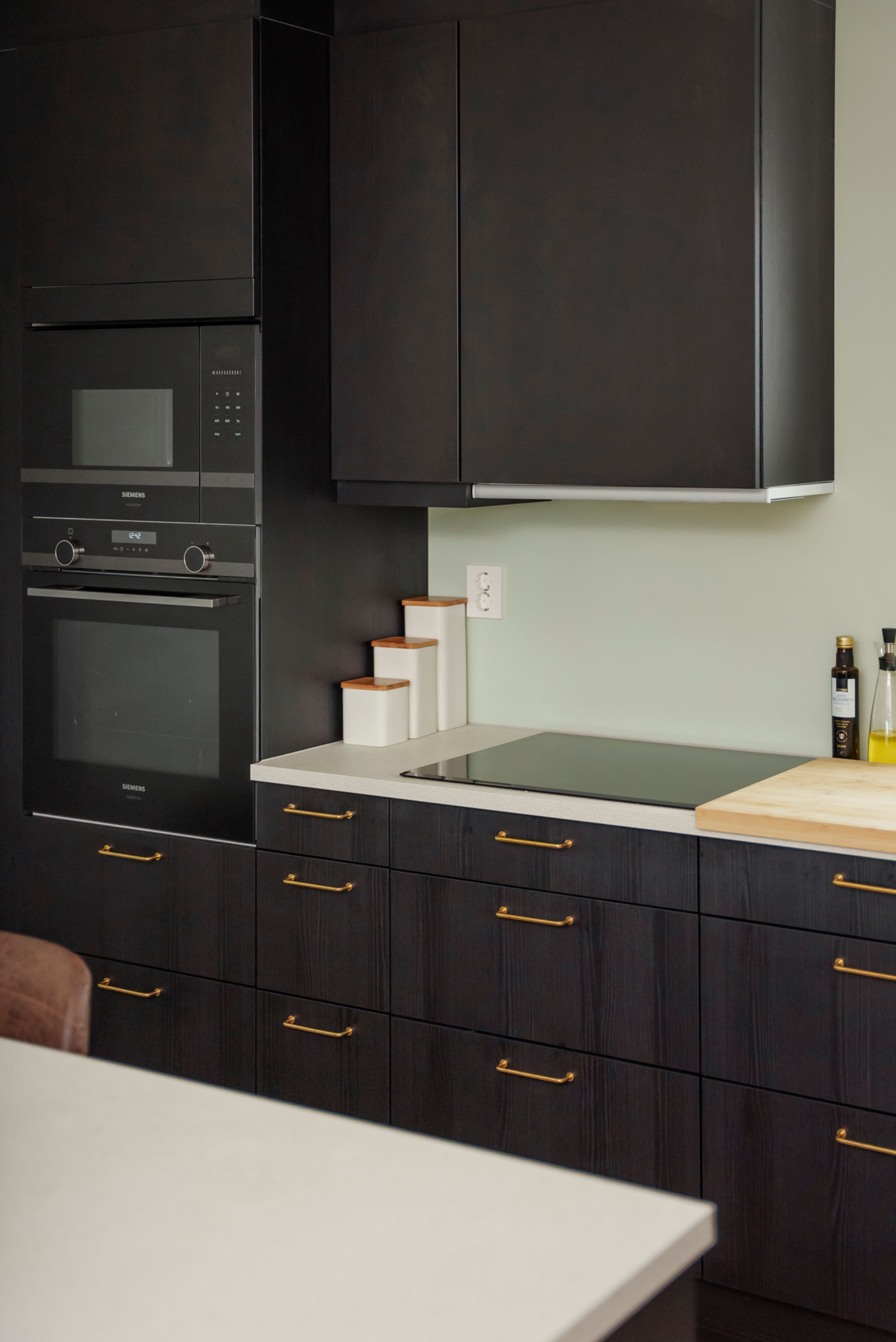 Kjøkkenet til Eirin med mørkebrune skapfronter og lysegrønne vegger i bakgrunnen.