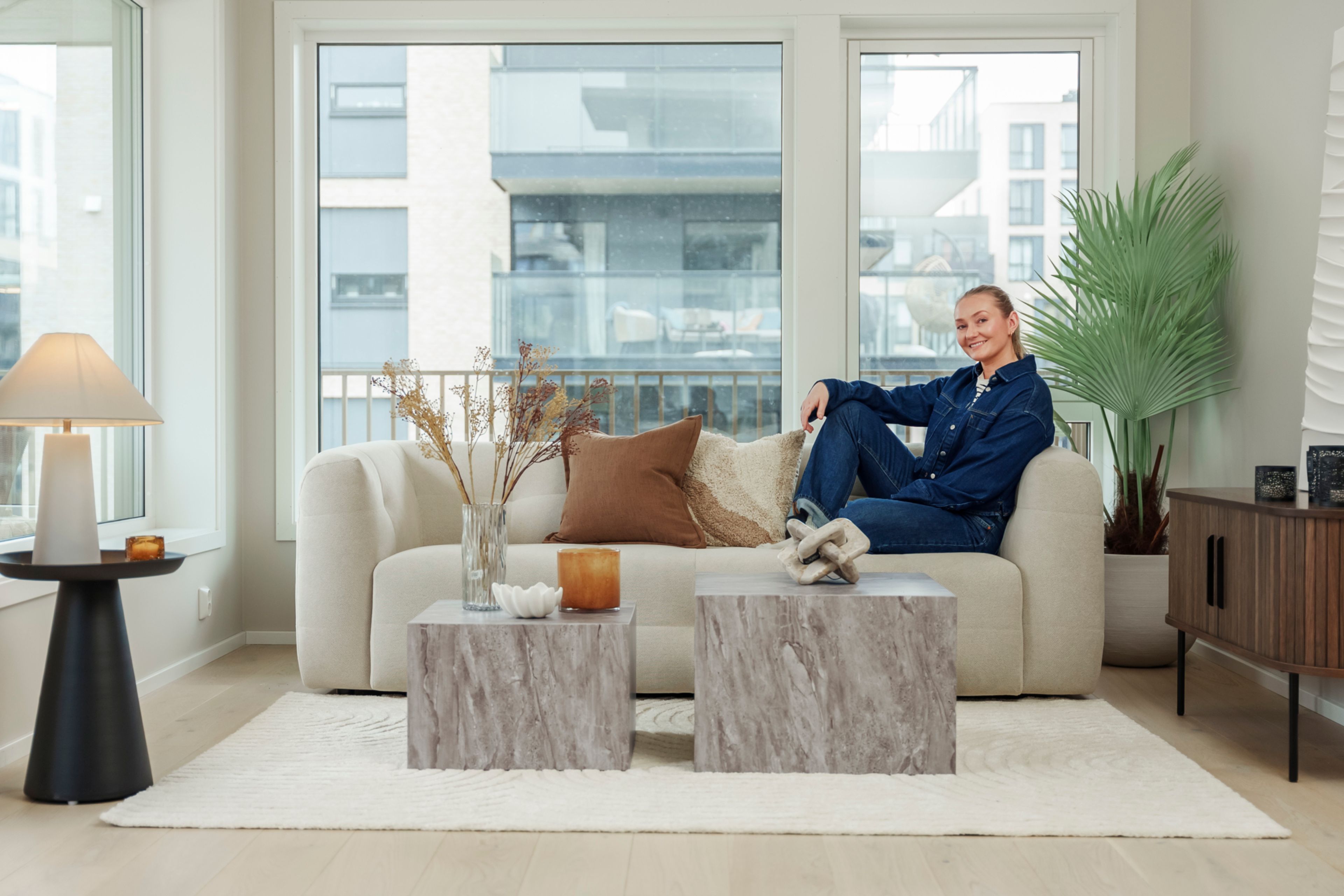 Stylisten fra Bohus sitter i en hvit sofa i en leilighet i MIDT.