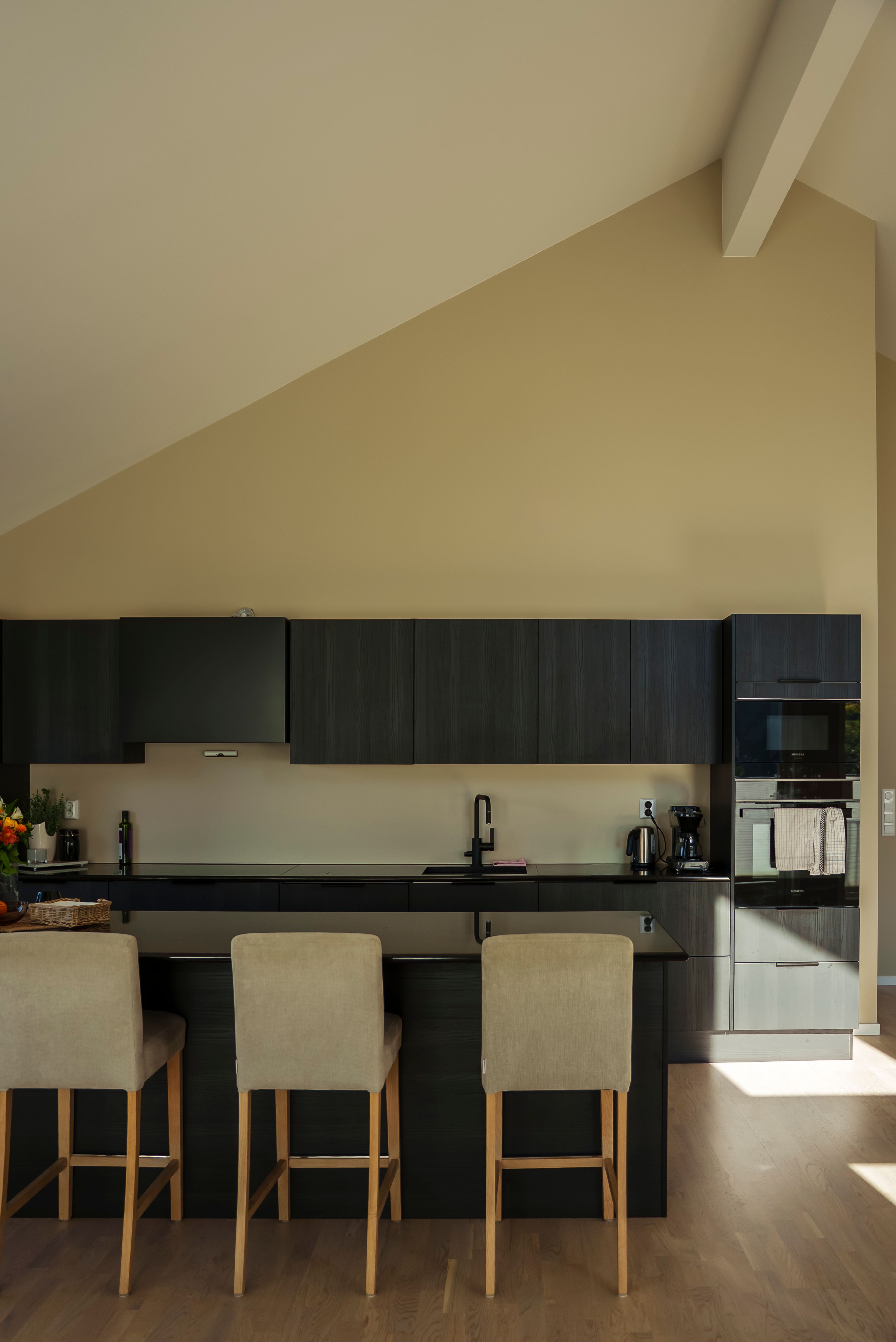 Oversiktsbilde av et moderne, svart kjøkken mot en beige vegg