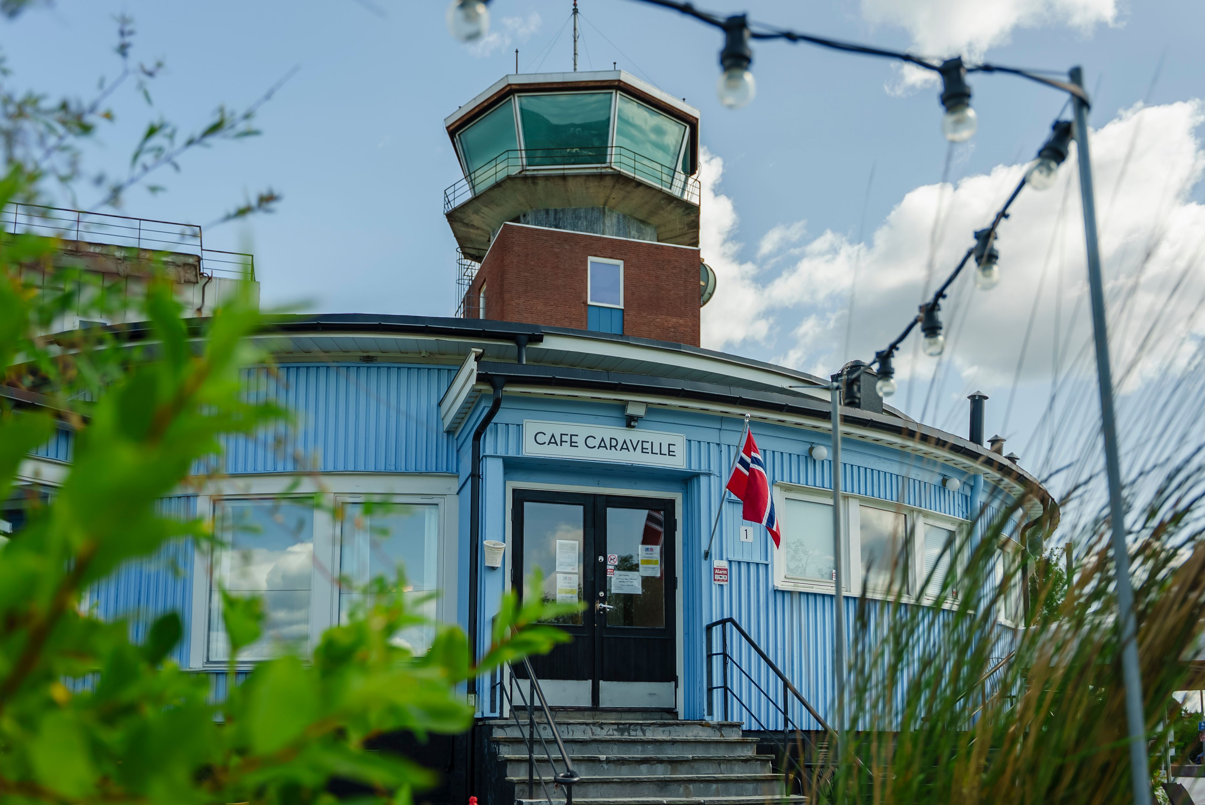 Foto av fasaden til Cafe Caravelle med Flytårnet i bakgrunnen