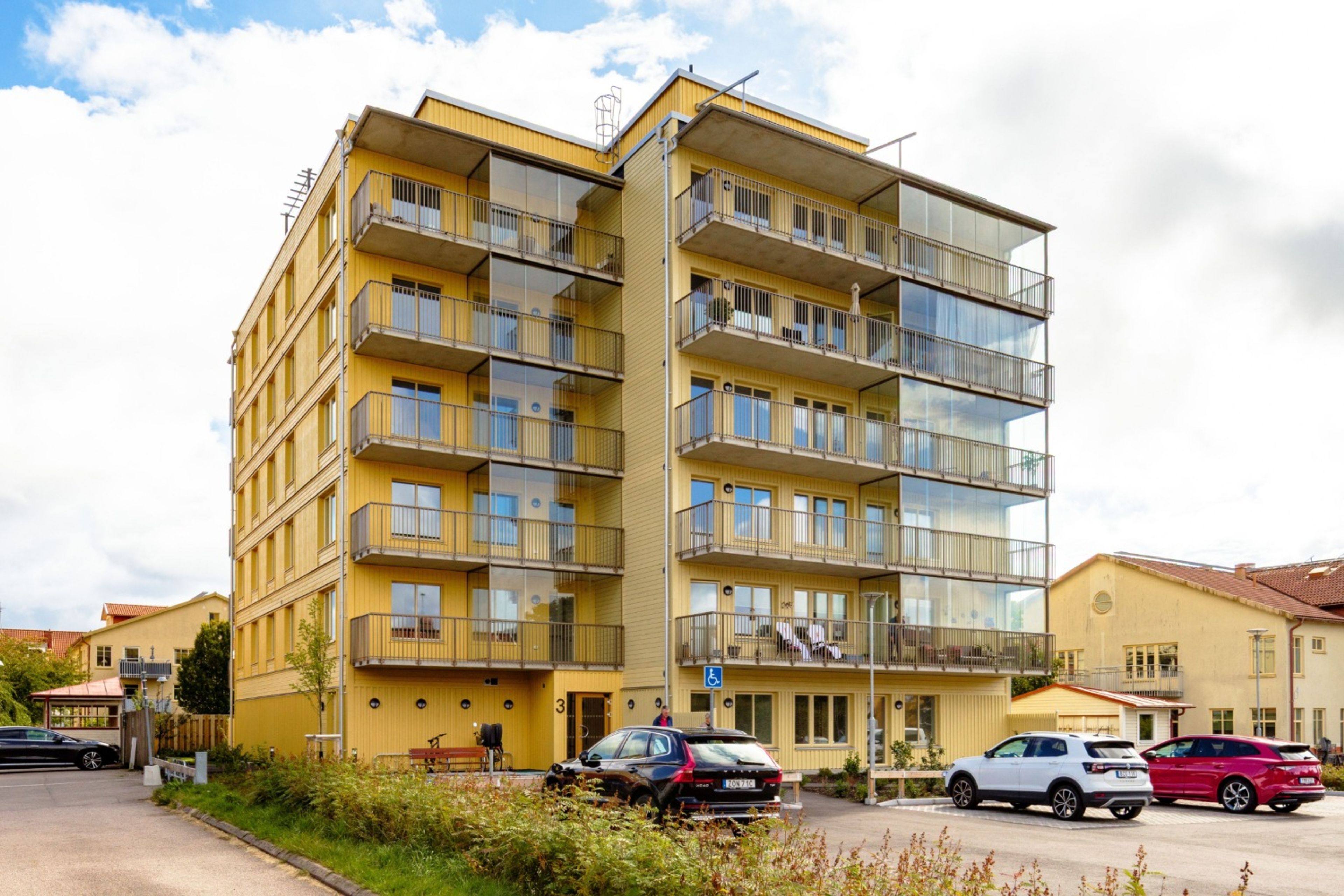 Foto av ett lägenhetshus med gul fasad och 7 våningar