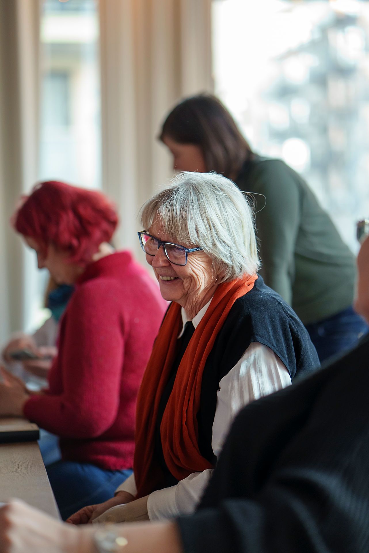 Bilde av Ulven-beboer Marit Holen på seniortreff, med to personer i bakgrunnen.