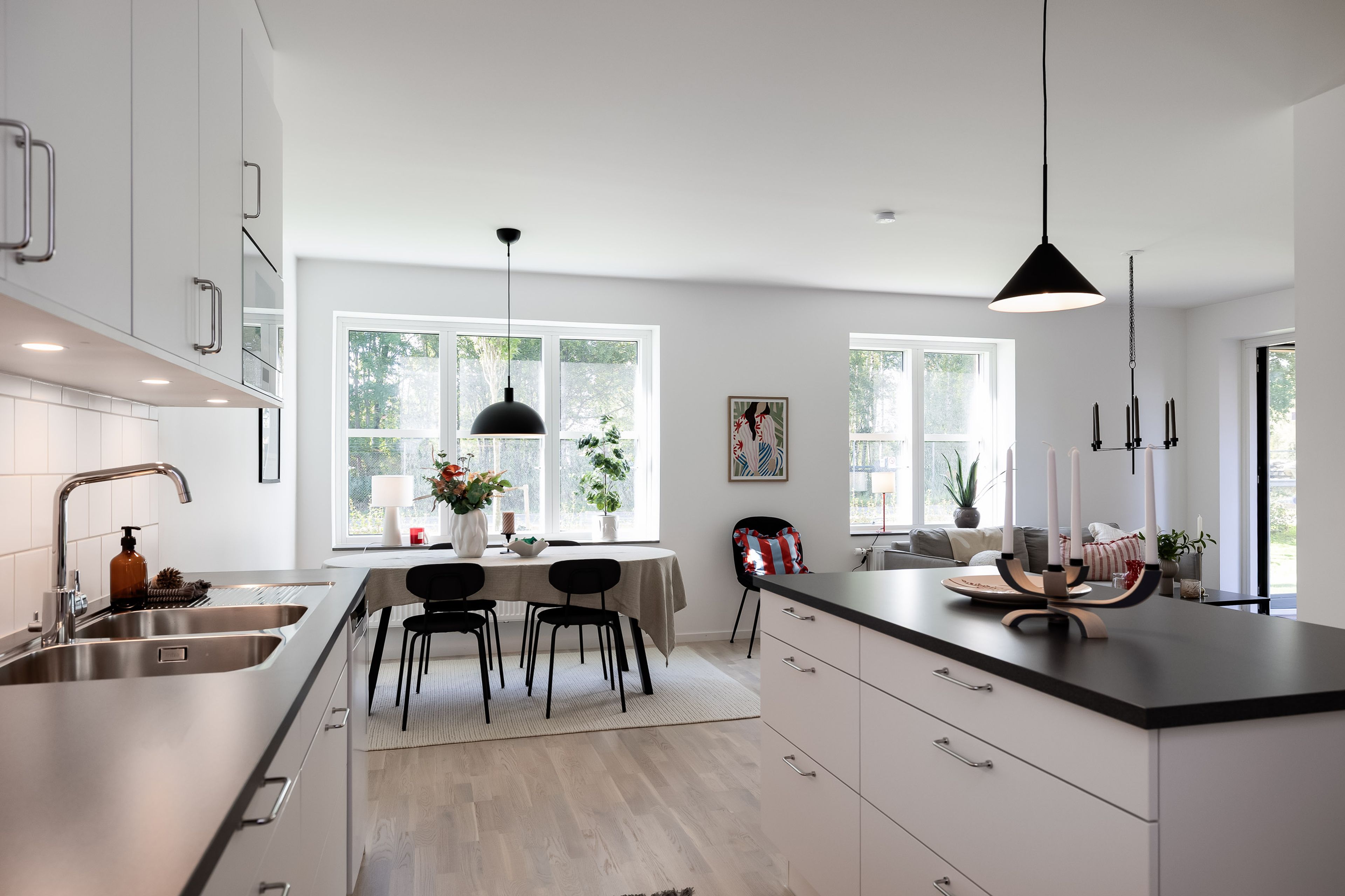 Foto på kök med köksö och matplats med bord och stolar framför stora fönster
