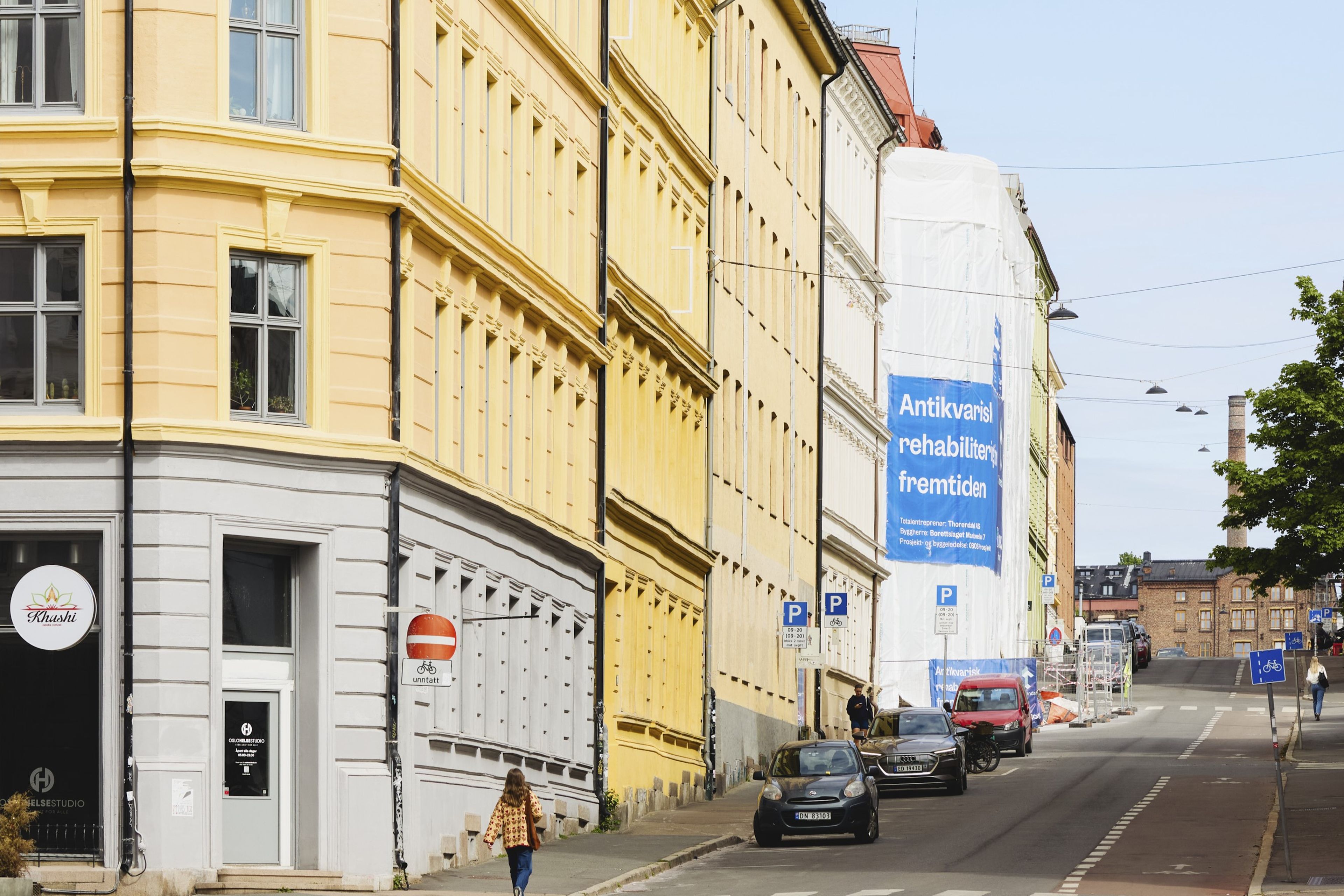 Flere gamle bygårder på rekke og rad oppover en bakke. En av bygårdene er under rehabilitering.