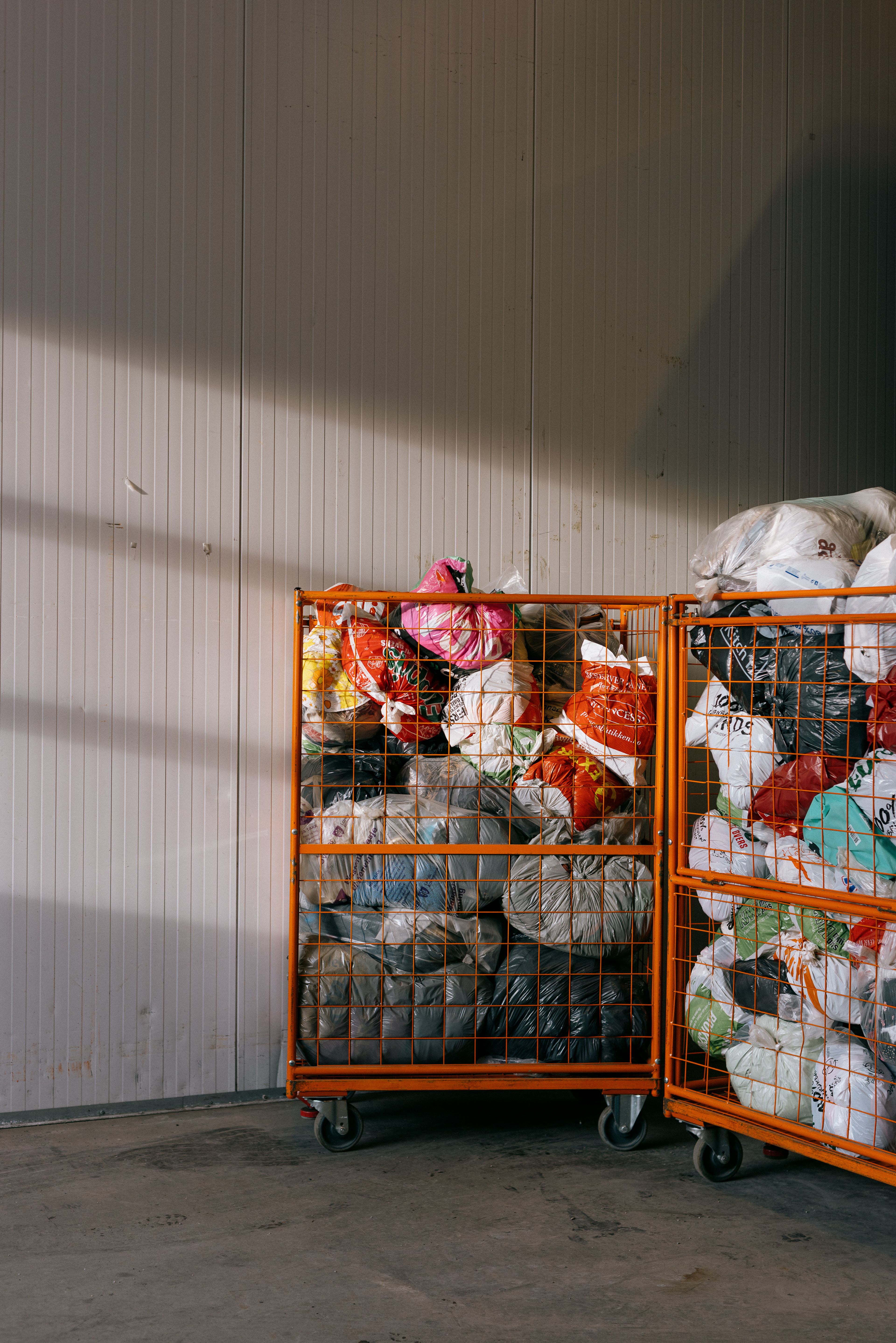 Foto av to oransje stråkurver som er fulle av innsamlet tøy pakket inn i ulike plastikkposer.