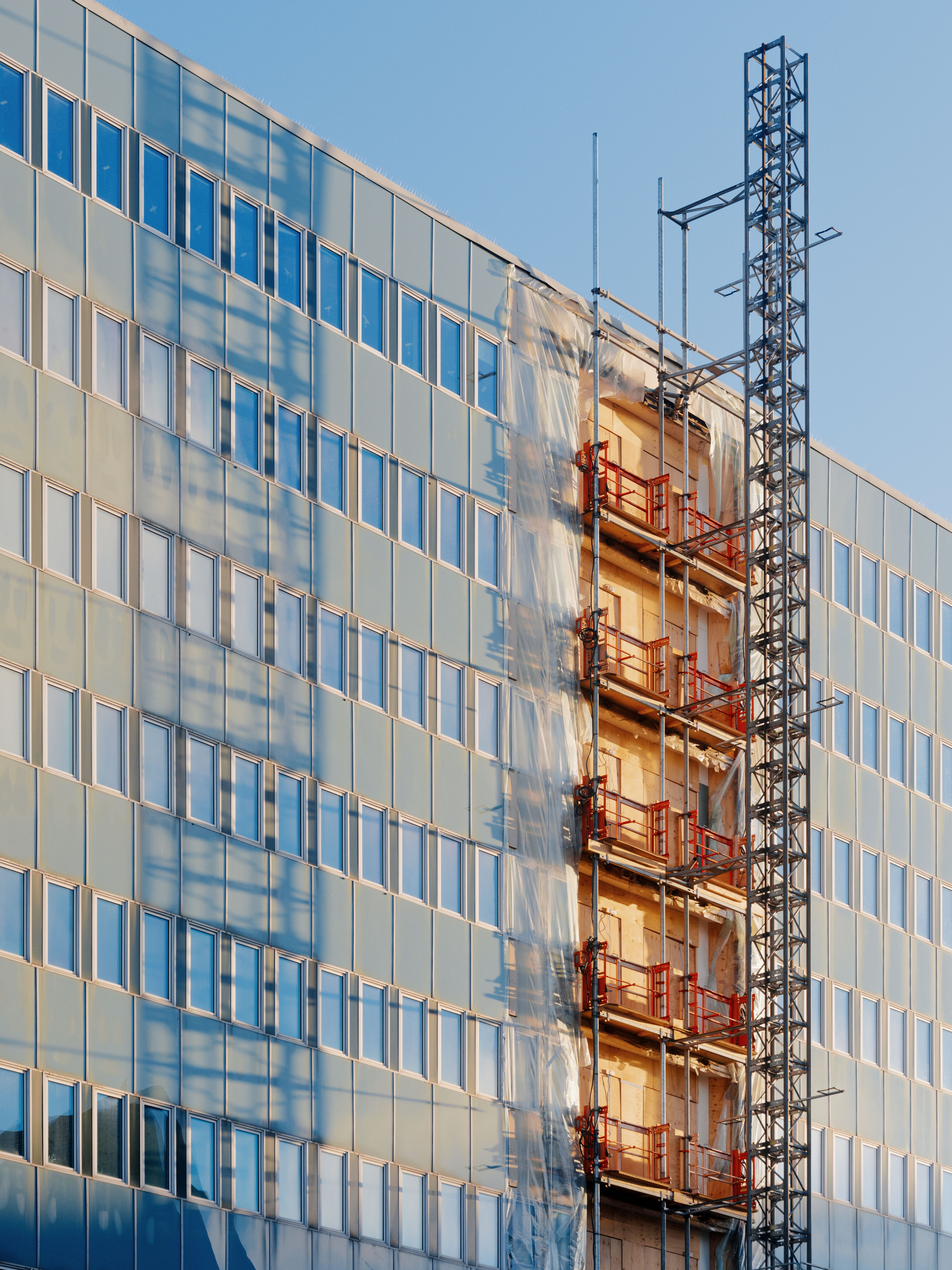 Foto av en fasade som pusses opp med nye balkonger.