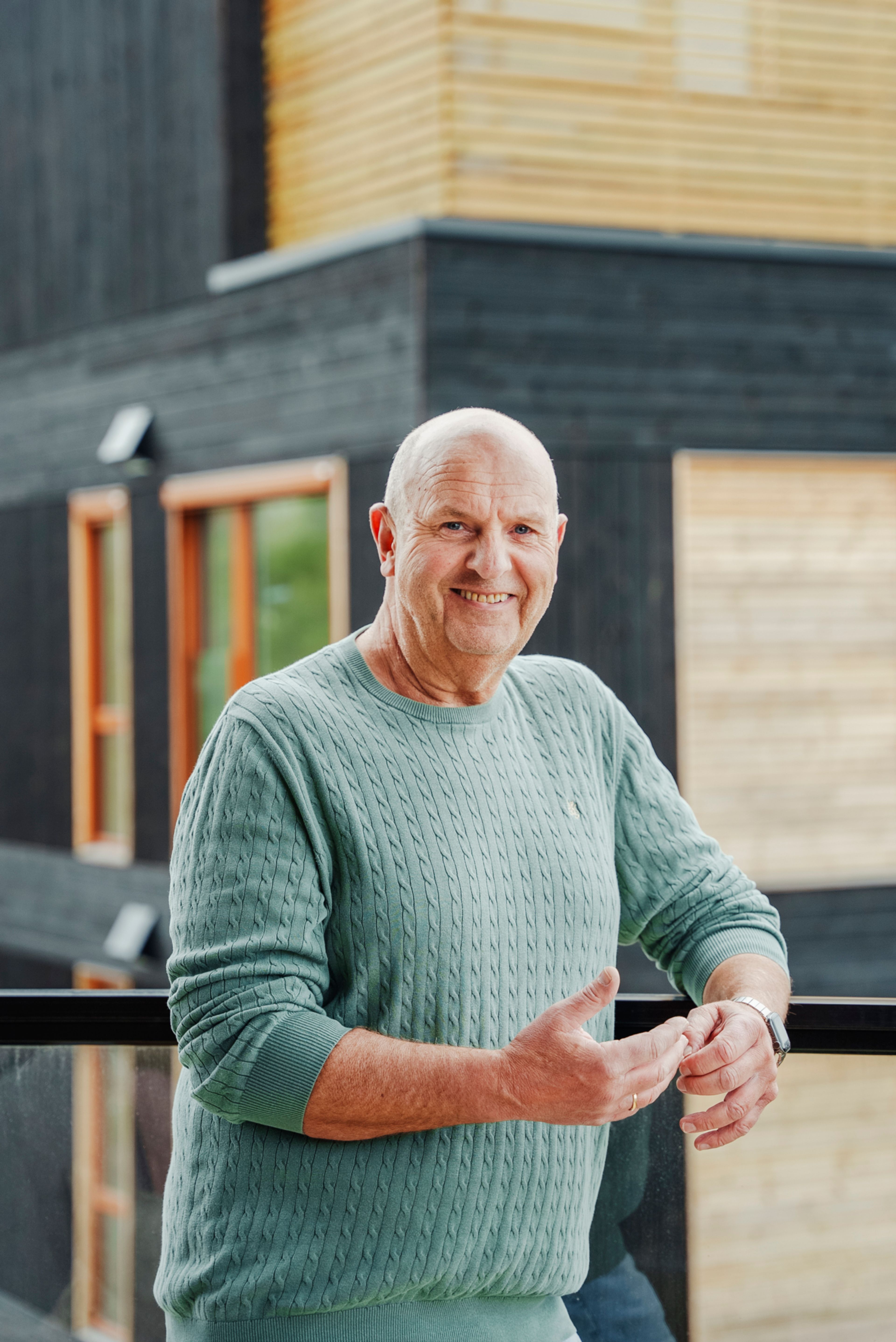 Prosjektleder Tommy Larsen smiler til kamerat på en balkong i Furukrona.