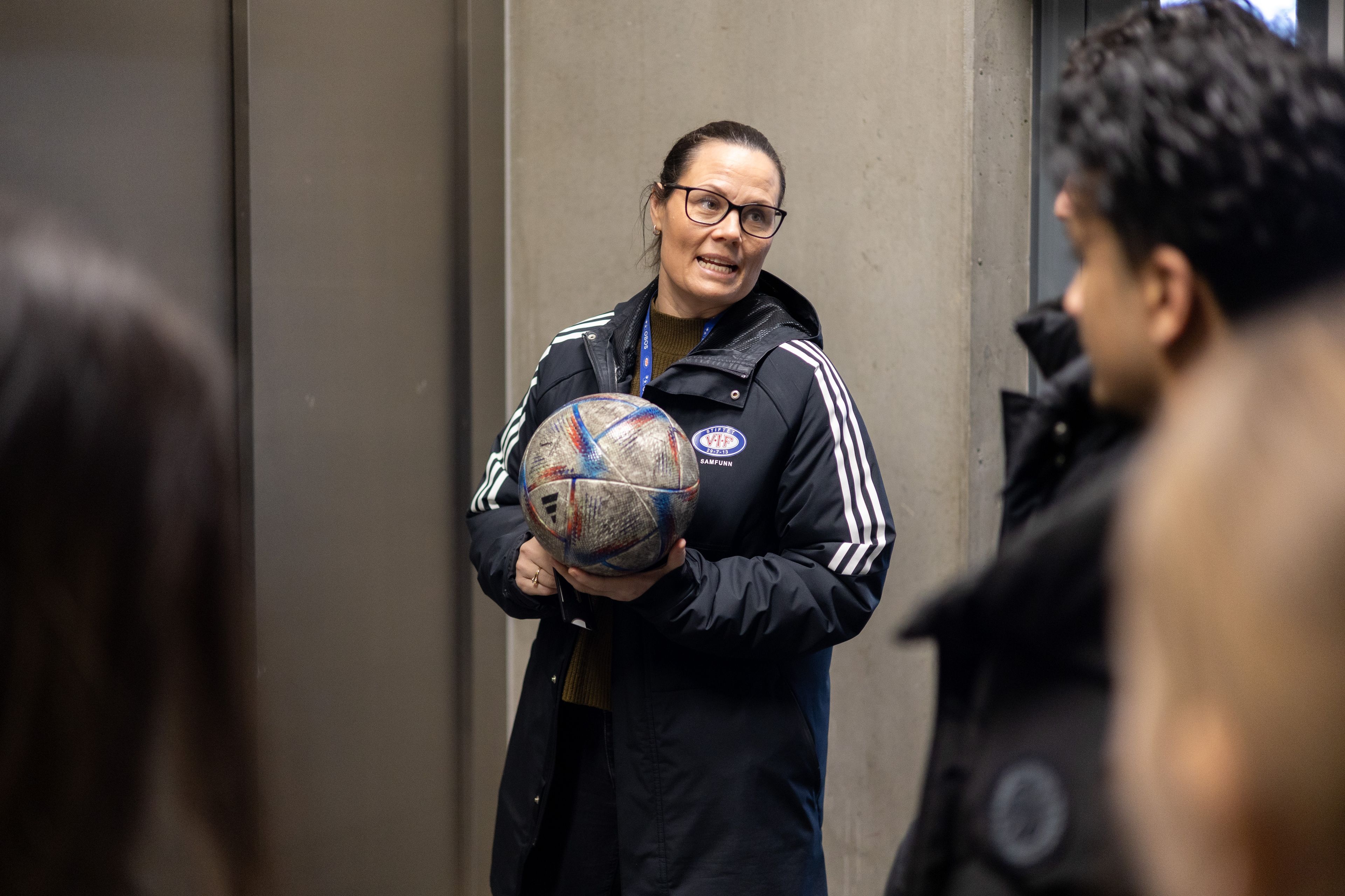Kvinne med ball i hendene snakker med ungdommene fra Haugerud skole.